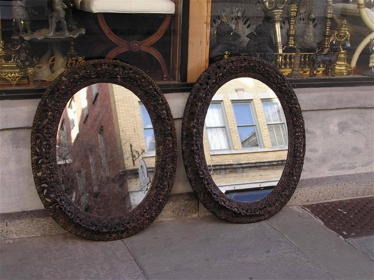 Paire de miroirs ovales en acajou finement sculptés de style anglo-indien, avec leur verre d'origine et leur support en bois. Début du 19ème siècle.