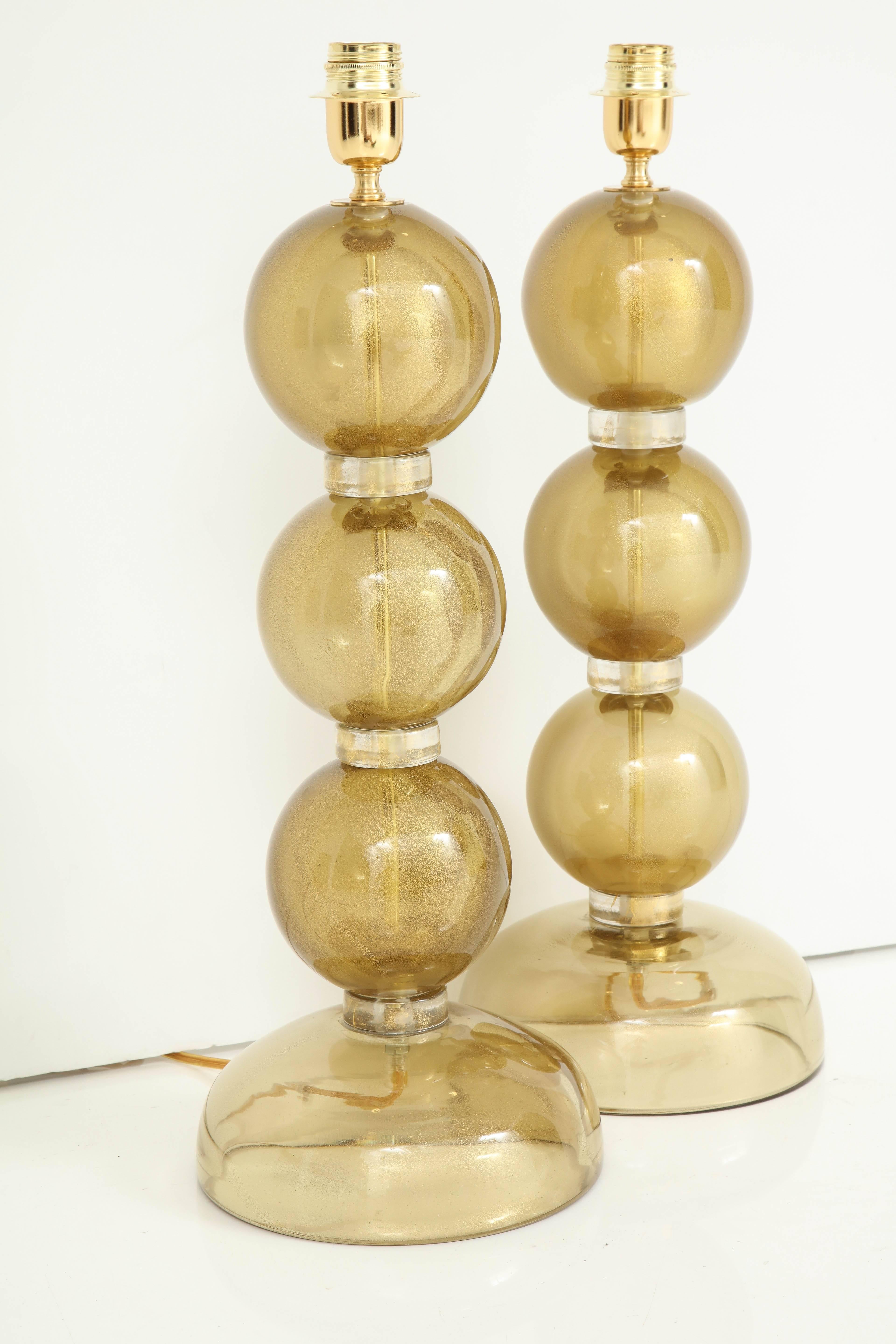 Paire de lampes composées de verre de Murano transparent soufflé à la main et infusé d'or 23 carats, créant un effet doré riche et lumineux. Chacune des trois sphères est séparée par des anneaux en verre avec des mouchetures d'or. Fabriqué à la main