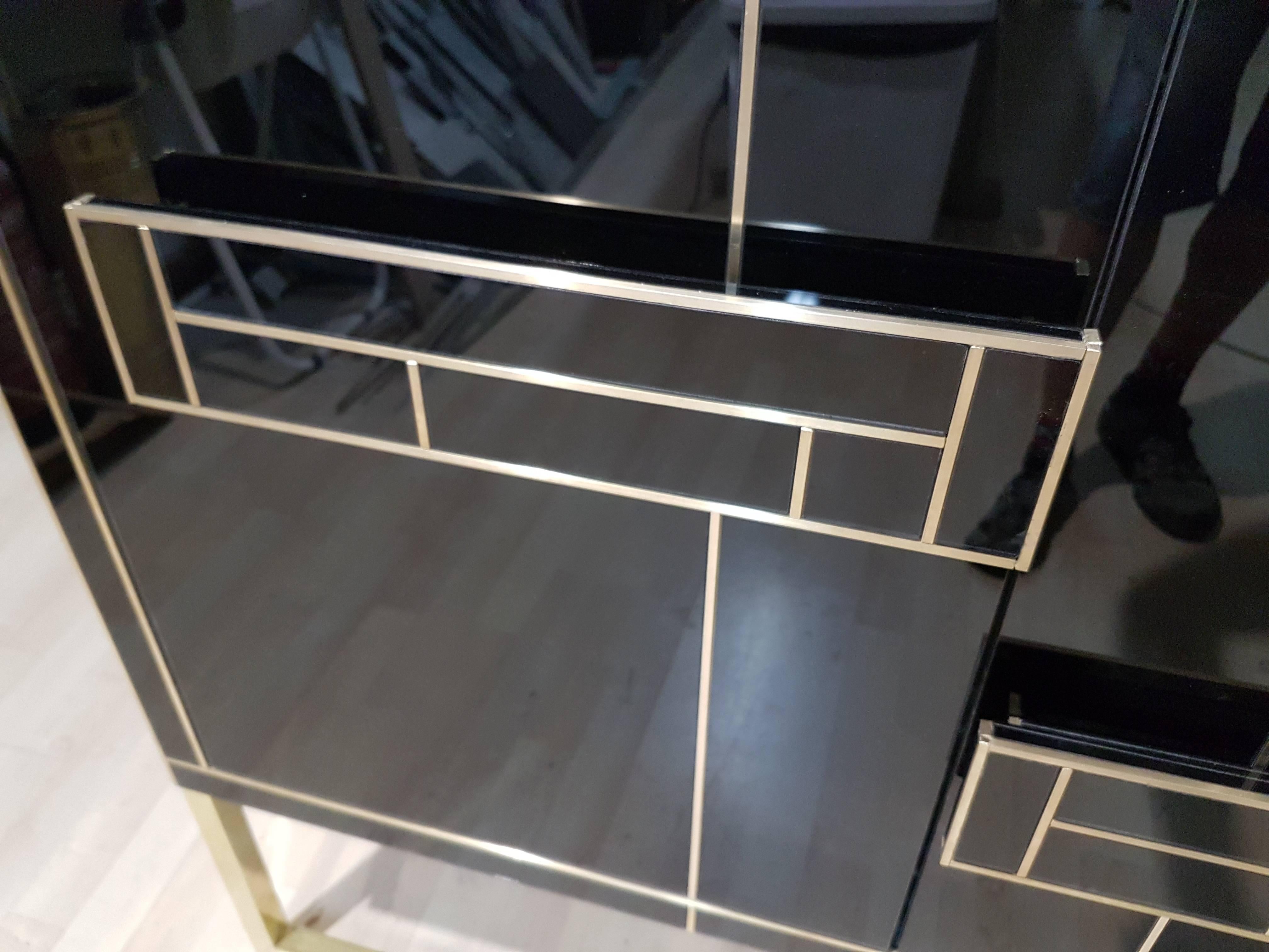 Elegant and timeless pair of black onyx glass cabinets with brass flat bar legs and brass inlays. Interior is plated in mirrors. Handcrafted in Spain exclusively for us. An exquisite work of art. Signed by artist/maker. These cabinets are versatile