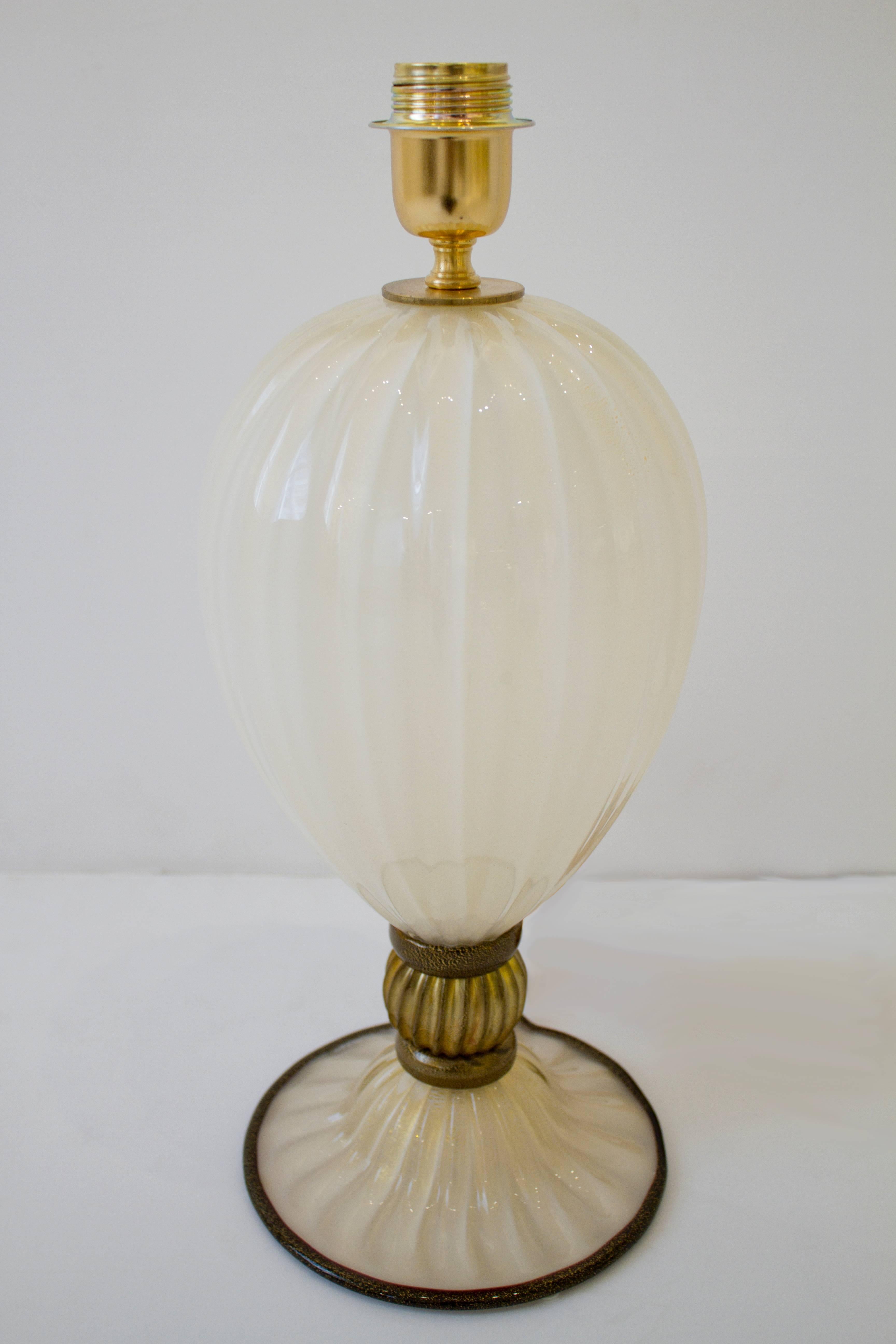 This pair of hand blown Murano glass lamps consist of shimmering Ivory glass base contrasted by a gold ridged sphere and dark bronze rings. 23-karat gold powder was infused in the ivory glass during the blowing process to create this shimmering