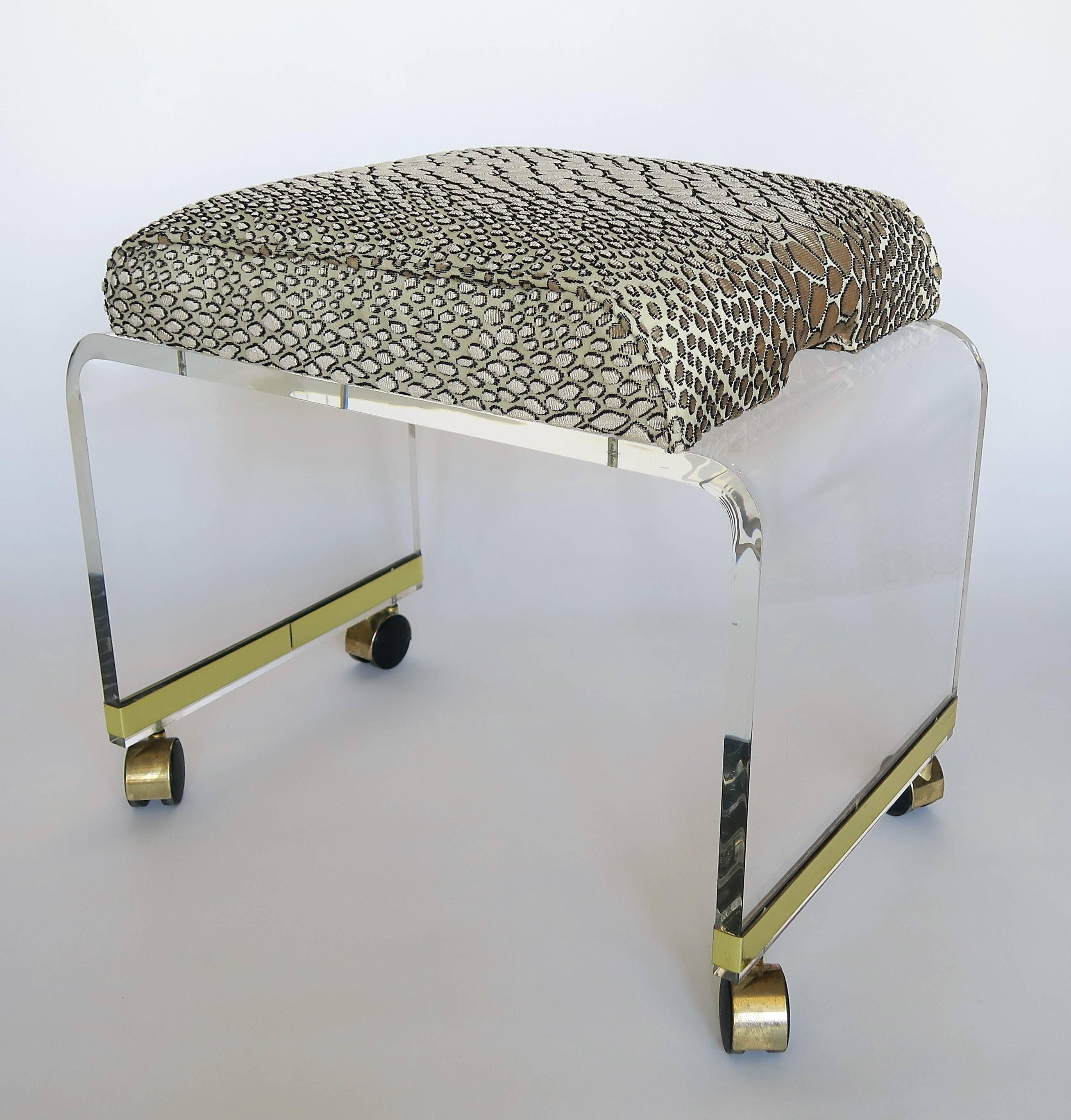 Elegant and chic, this gleaming Lucite stool or bench is attributed to Charles Hollis Jones. Original brass plated casters. Lucite is in excellent condition with a few minor scratches from age that cannot even be photographed. Newly upholstered in a