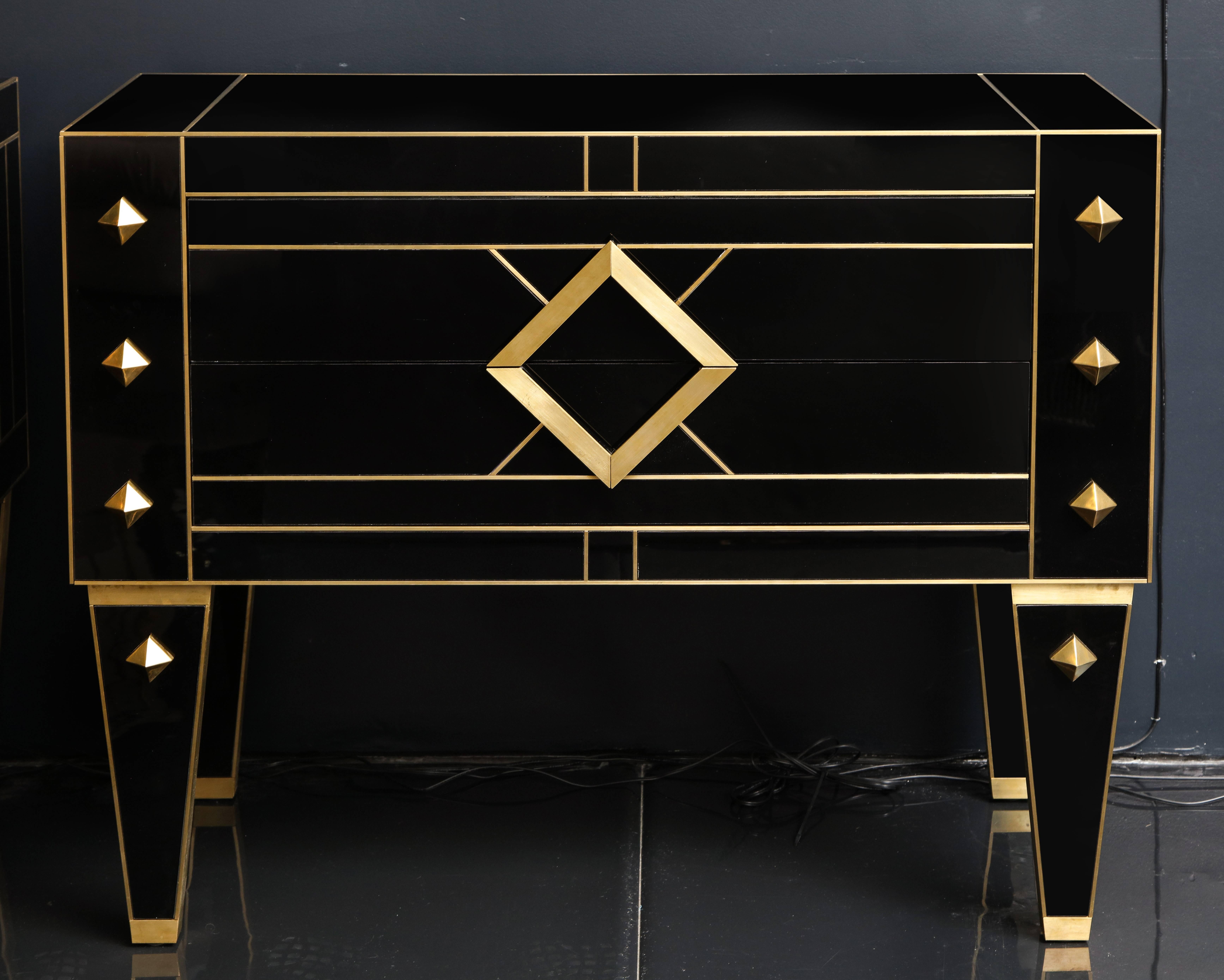 Elegant and timeless pair of black onyx glass chest of drawers with tapered legs and brass inlays. Two drawers lined in glass and mirror. Handcrafted in Spain exclusively for us. An exquisite work of art signed by artist/maker.

These elegant pair