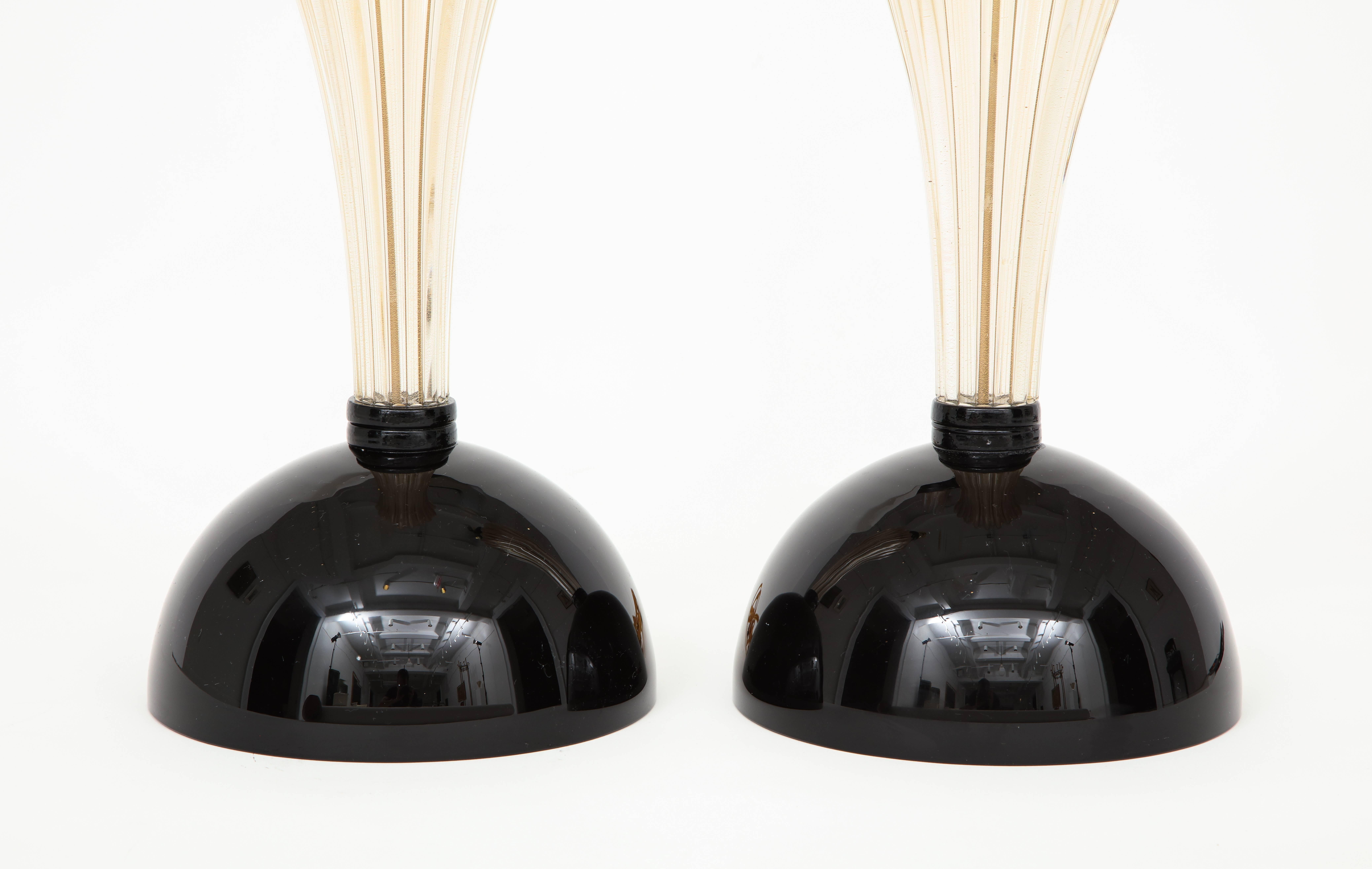 This pair of hand blown gold and black Murano glass lamps combine timeless Classic design with a modern twist. A clear Murano ridged glass center is infused with 23-karat gold flecks, giving it a shimmering jeweled look.
Two solid black Murano glass