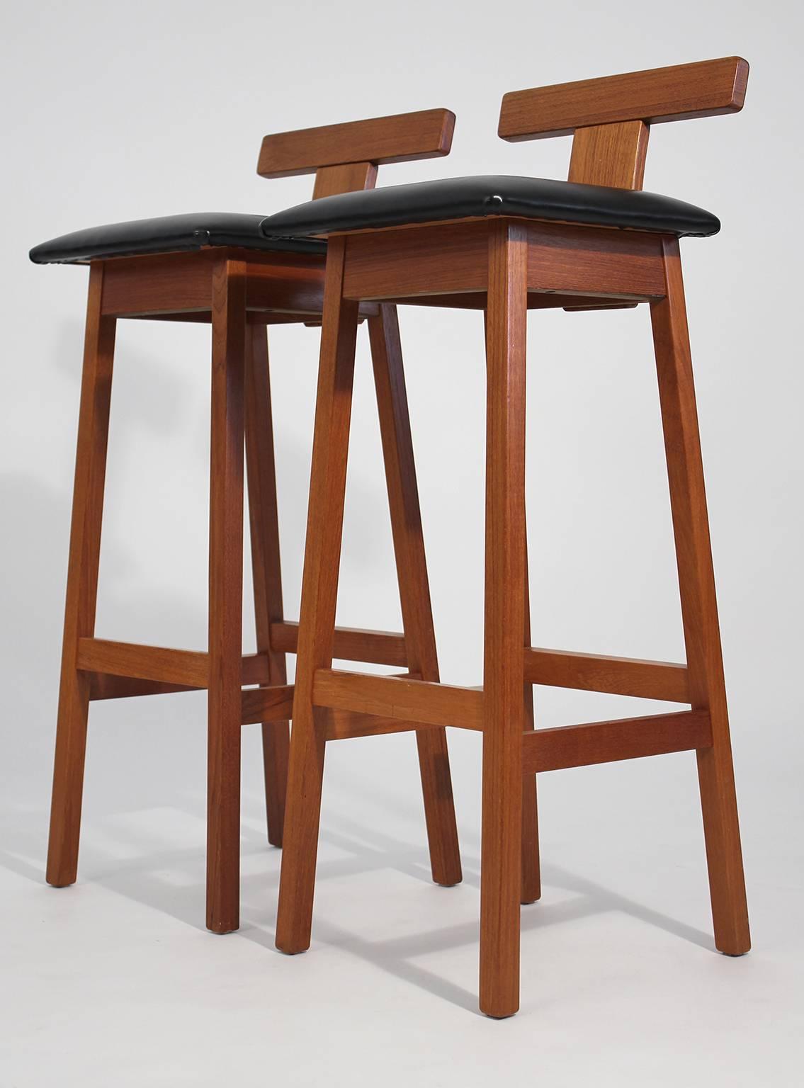 Pair of Dyrlund solid teak Danish bar stools. In excellent original condition with the original black vinyl seat. Great modernist design.