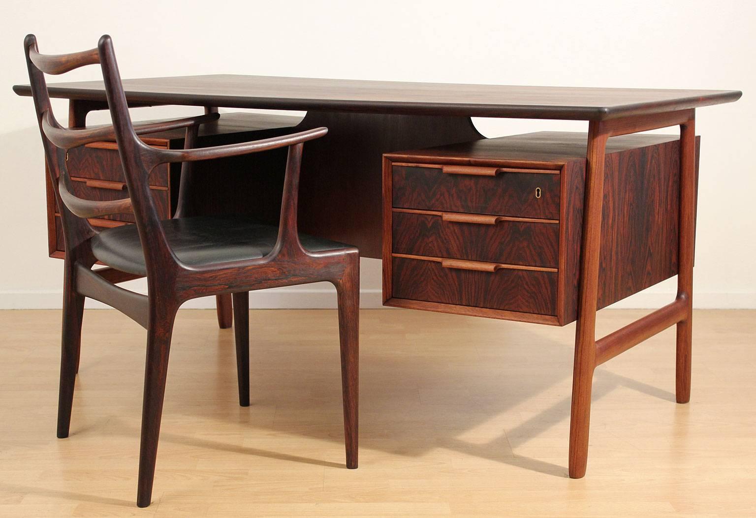 Excellent designed Danish rosewood executive desk and chair by Gunni Omann for Omann Juns Møbelfabrik, Denmark, circa 1960. Desk has the original key to lock the drawers. Has book shelves on the front of the desk with a center compartment. Wonderful