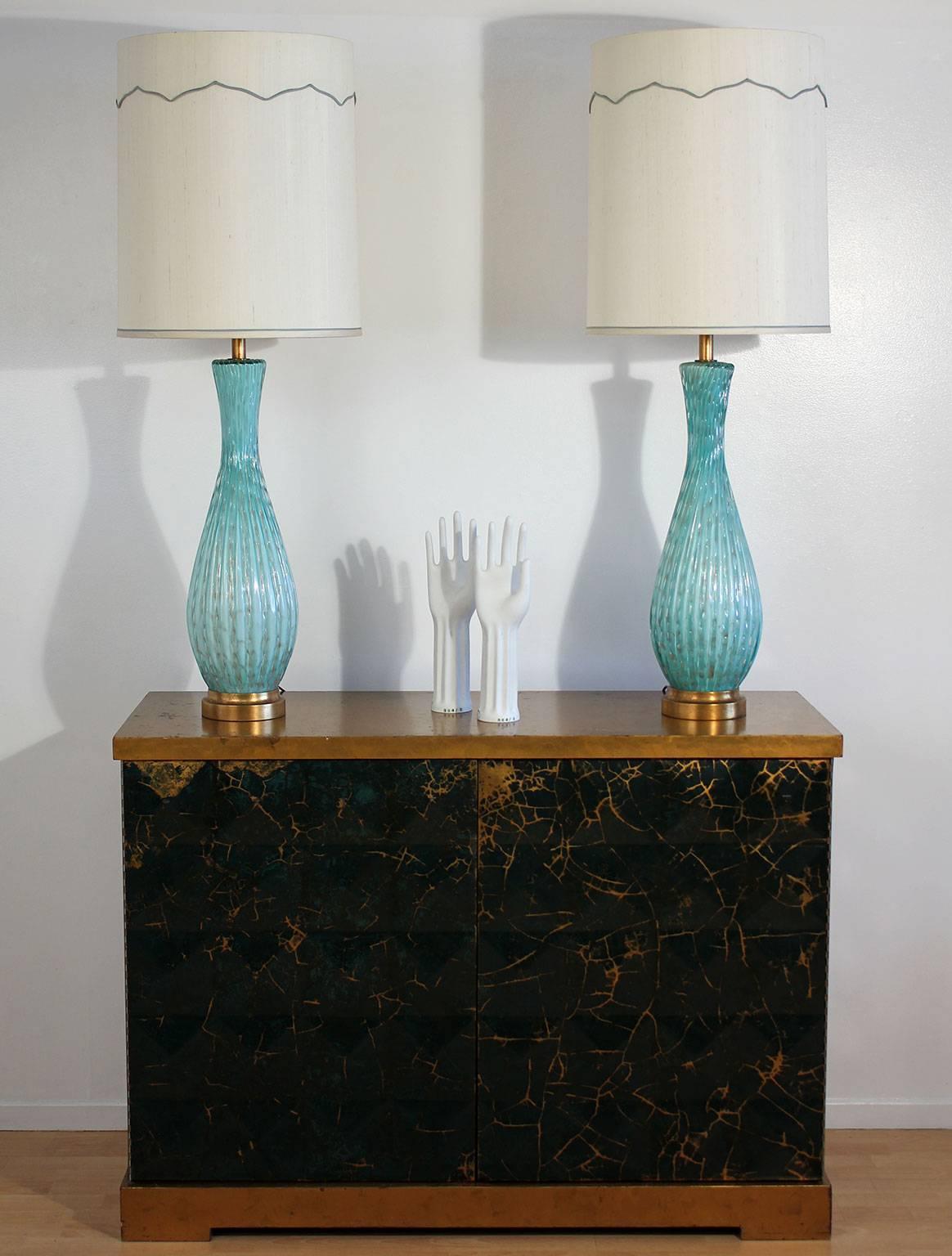 Beautifully preserved pair of tall Murano light blue art glass table lamps with controlled bubbles and gold inclusions. Original custom shades. Excellent all original condition, circa 1950s, Italy.

Overall dimensions with shades: 47