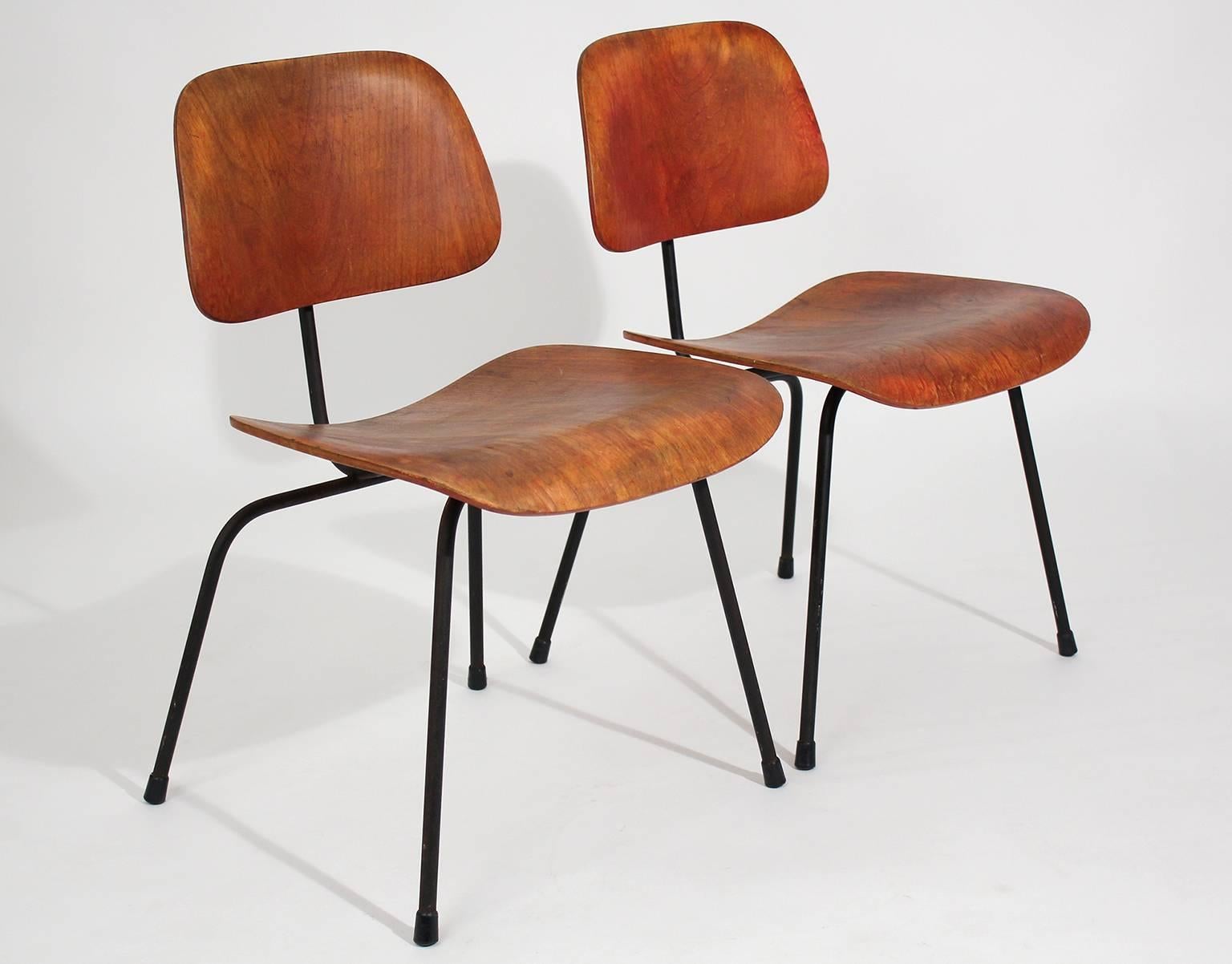 Great pair of early original Charles Eames for Herman Miller Aniline red DCM dining chairs with awesome patina. These are very early and would be great as accent chairs. The mounts are in great shape and are very strong. Patina is beautiful. Shows