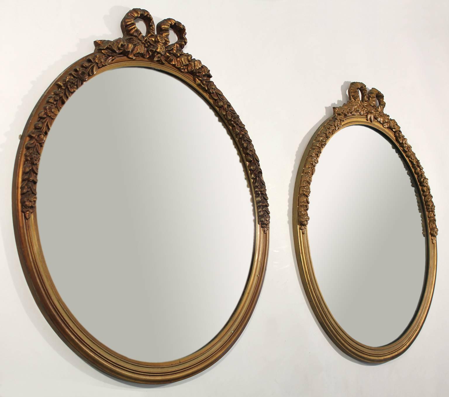 Great original antique pair of gold gilt painted carved wood mirrors. Beautiful ribbon/bow decorations done in plaster over wood. Has the original mirrors. In the style of French Baroque. These are 100% original and in very nice original condition.