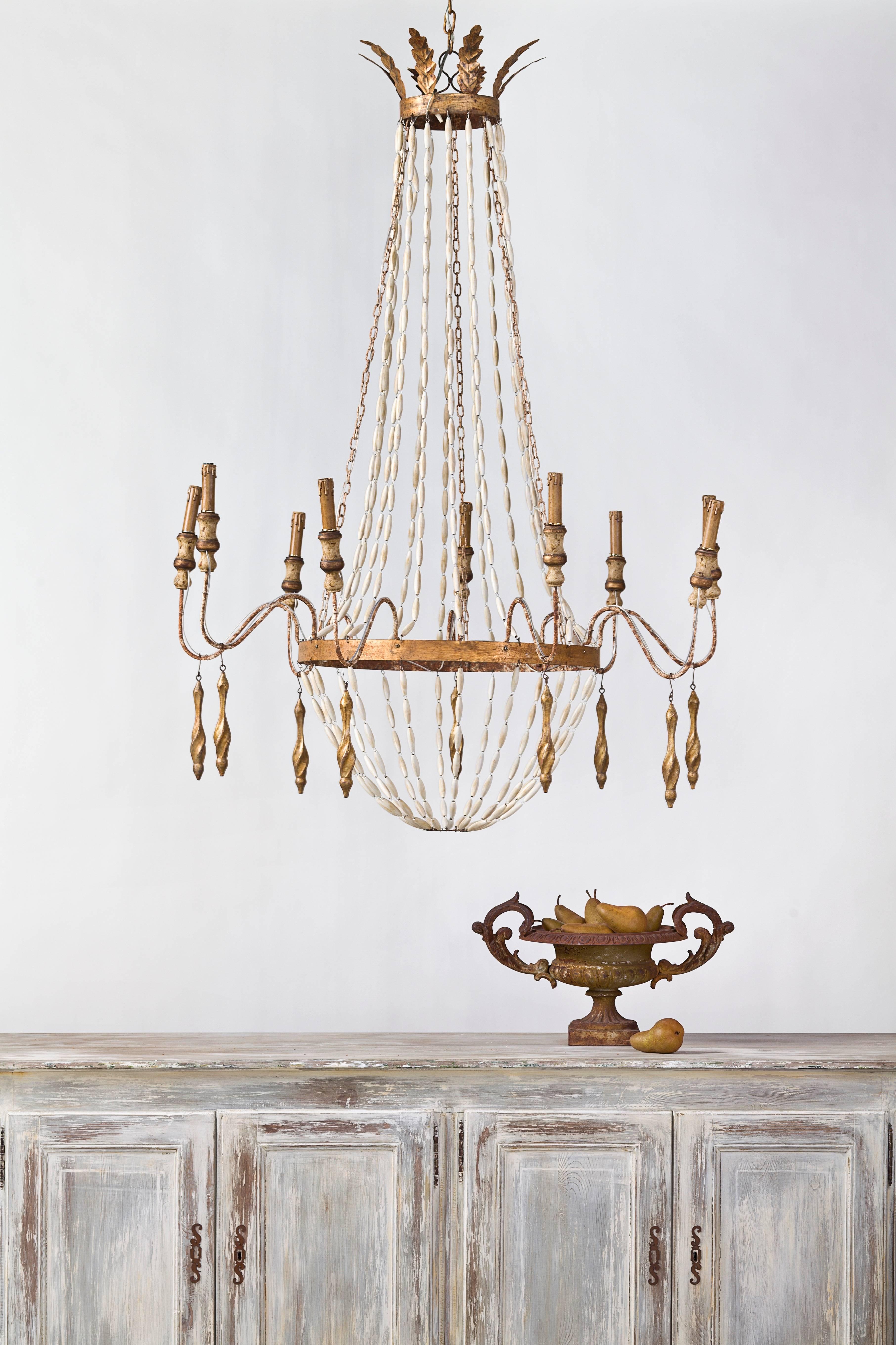 Beautiful reproduction nine-arm wooden beaded chandelier with gilded tassels and metal leaf crown. Currently not wired for US Electrical.