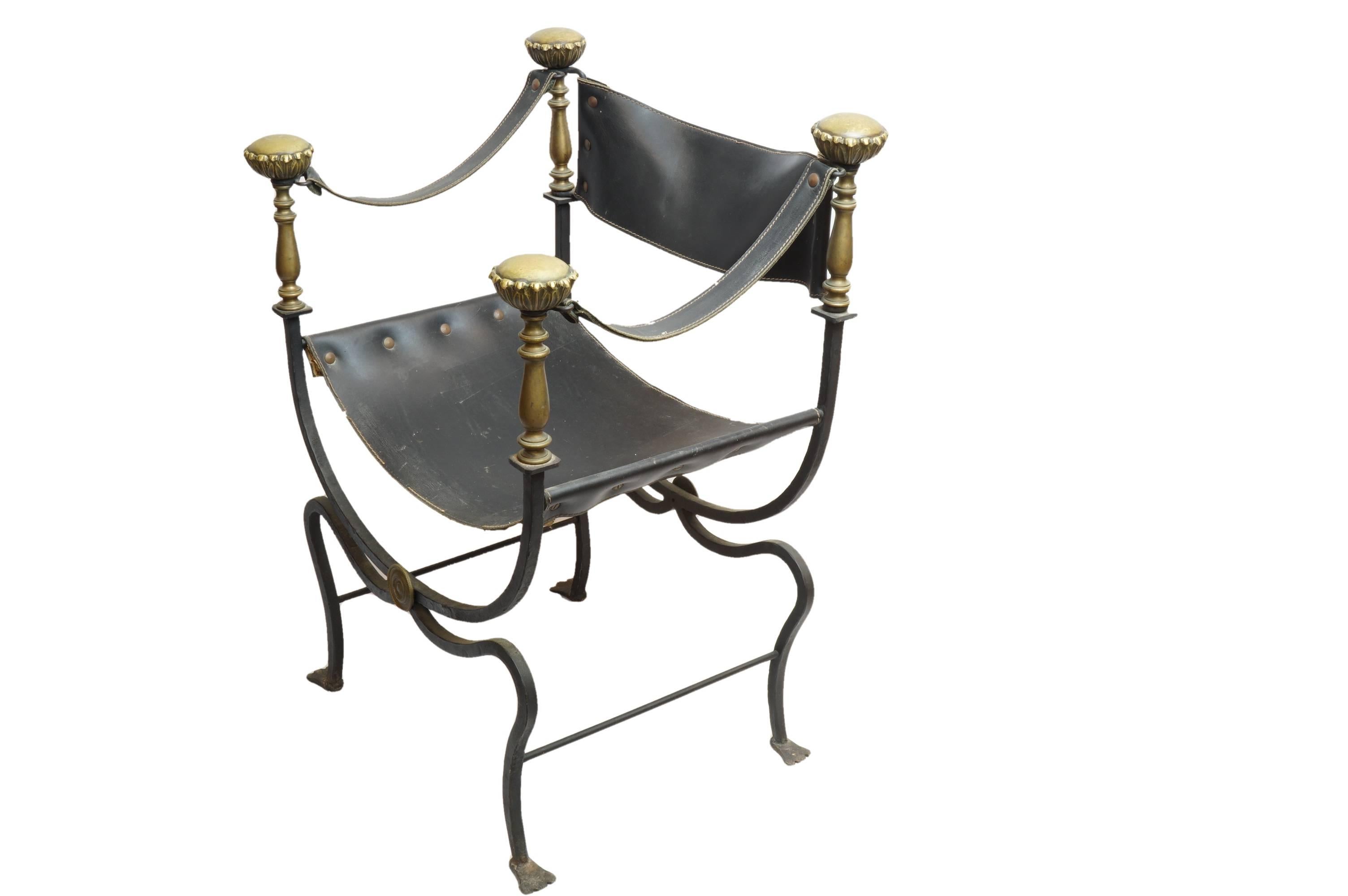 19th century pair of campaign chairs with leather seats, arms and back. Chairs feature wrought iron bases leading to bronze details and feet, with large bronze floral medallions crowning the armrests. Regal yet simplistic, this storied pair will