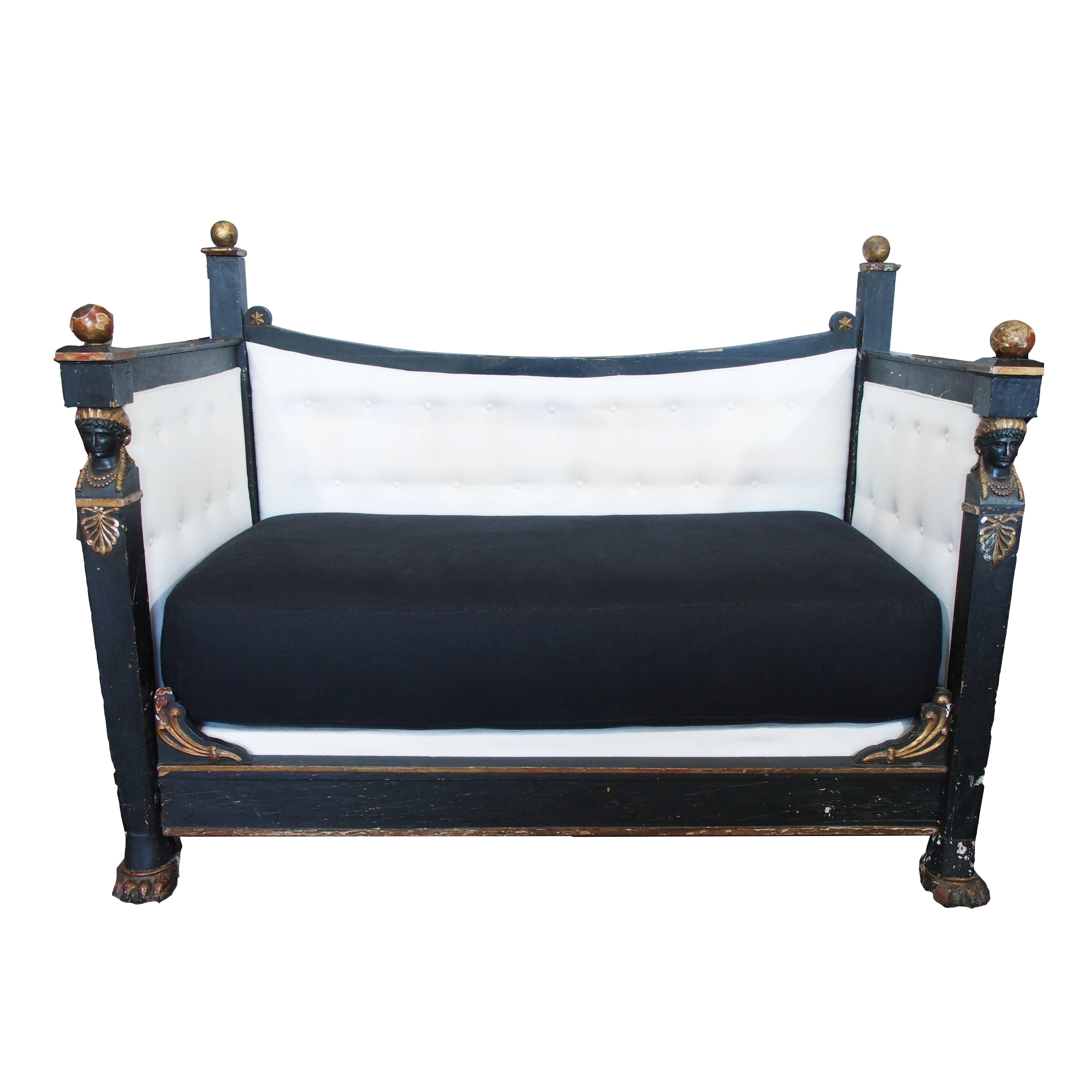 Tara Shaw Antiques - 19th Century Italian Noir Empire Banquette. Beautiful painted wooden banquette or daybed purchased in Palermo, Italy has detailed figurative carvings and round gilded finials. Includes custom box spring and mattress. Wear