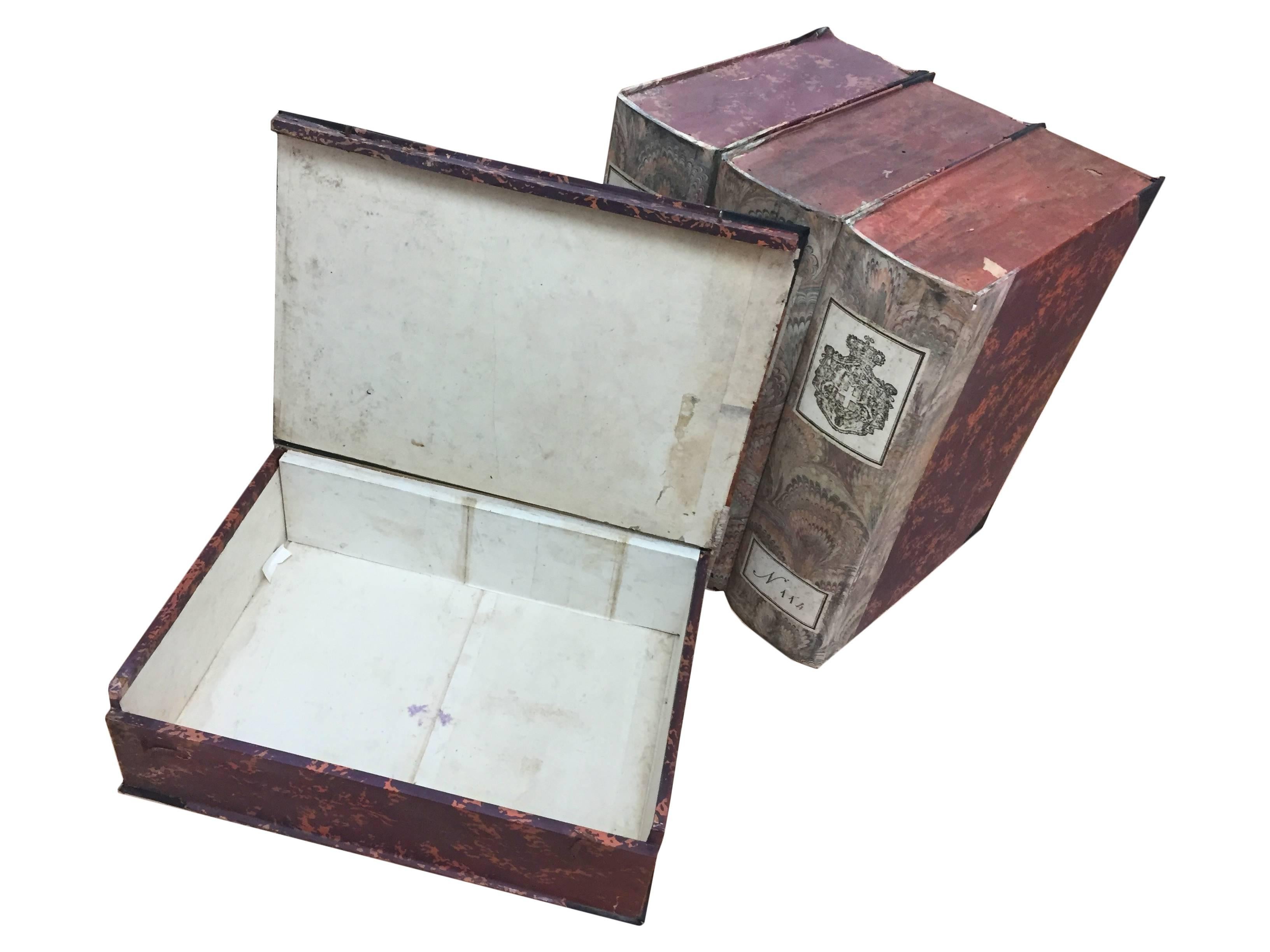 Set of four vintage 19th century, Italian faux book boxes that open at the cover for ample storage. Boxes are covered in beautiful red marbled paper, and are adorned with a Classic crest and numbered on the spine. Use as storage on a bookcase or