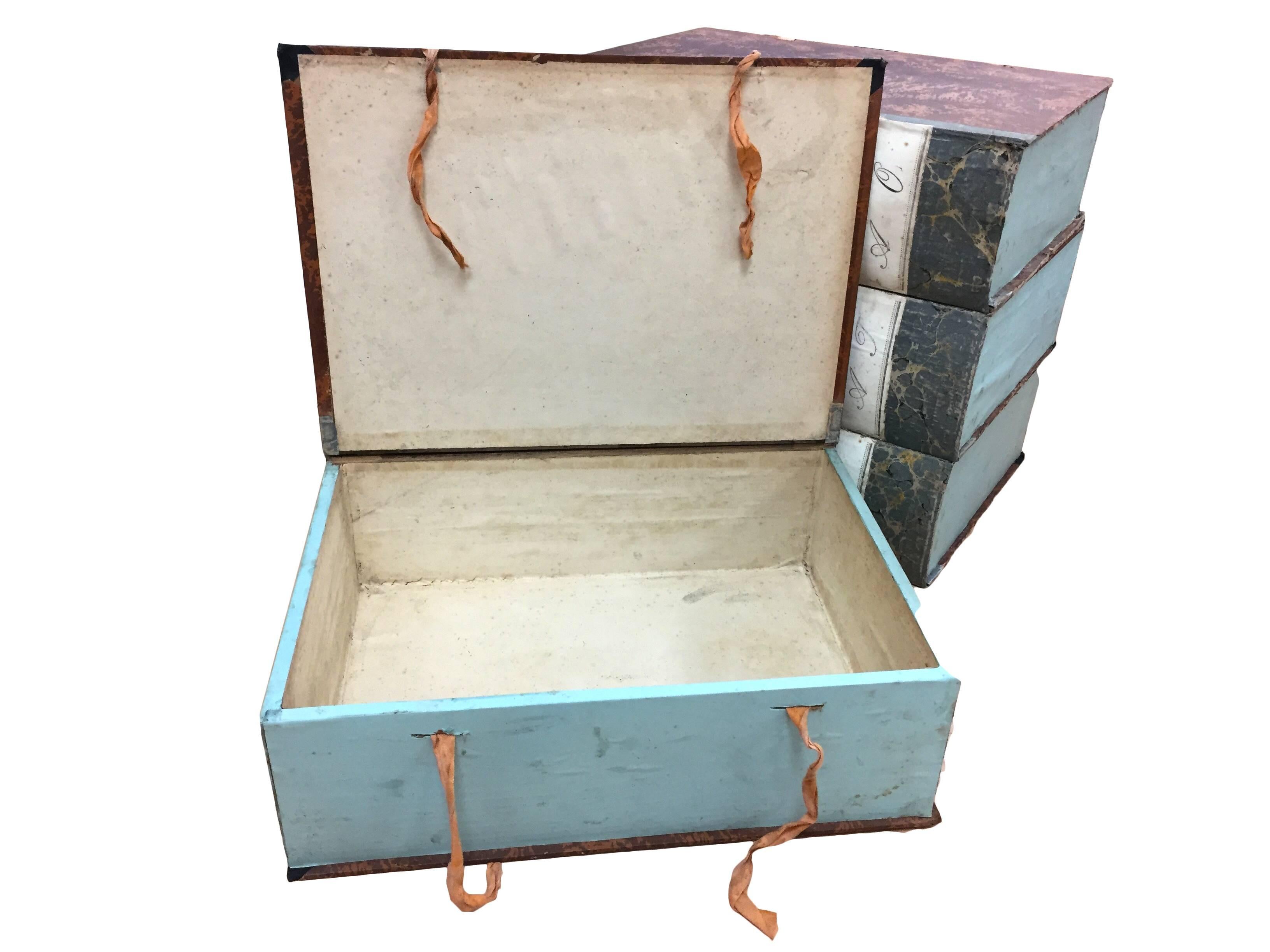 Tara Shaw Antiques - Set of four vintage to 19th century Italian faux book boxes that open at the cover for ample storage. Boxes are covered in beautiful red marbled paper, and are adorned charming ribbon closure and beautiful script on the spine.