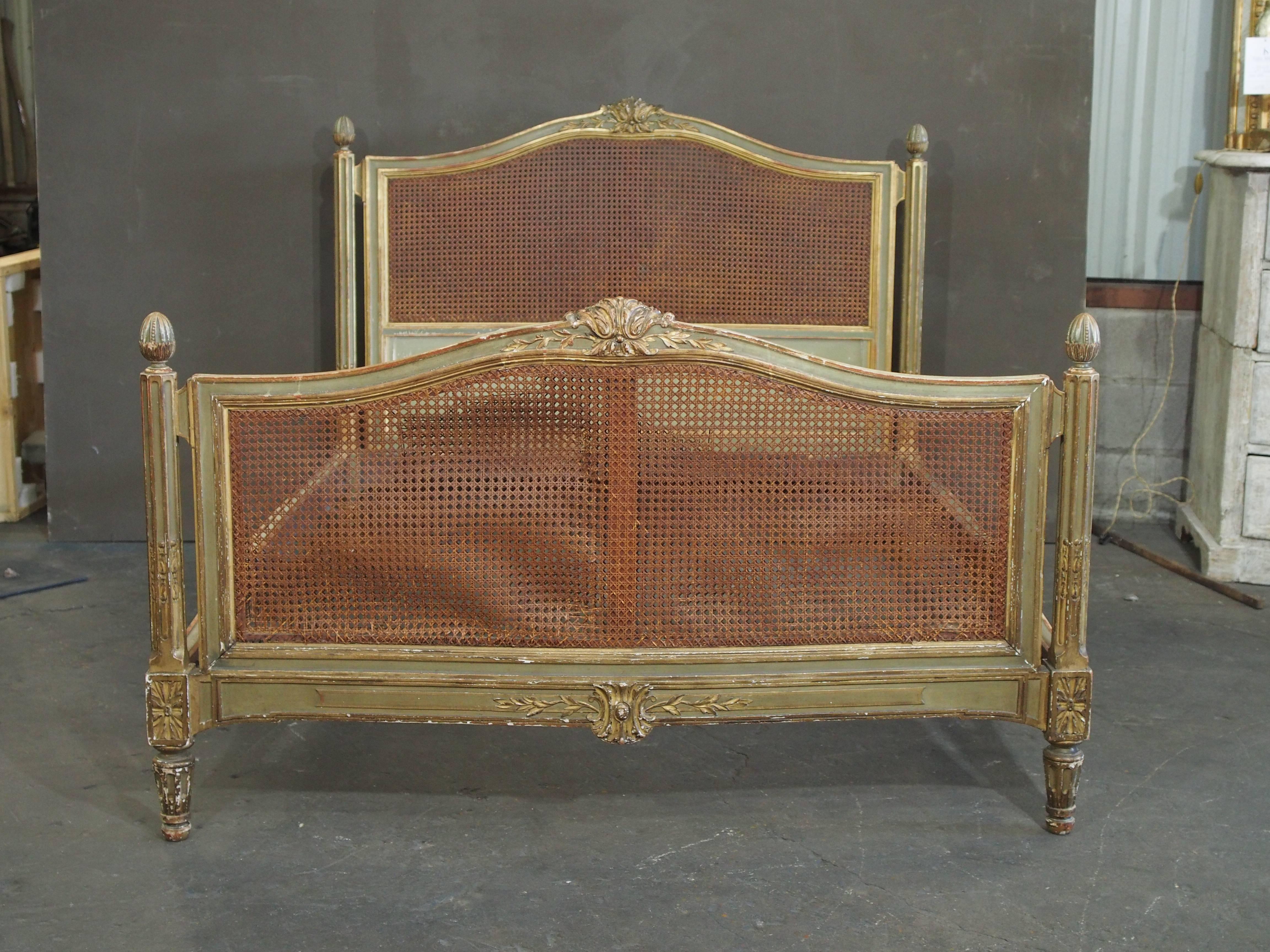 Majestic Louis XVI bed with a caned headboard and footboard. Features delicate carving with gilded accents. Some damage to caning inside of footboard.