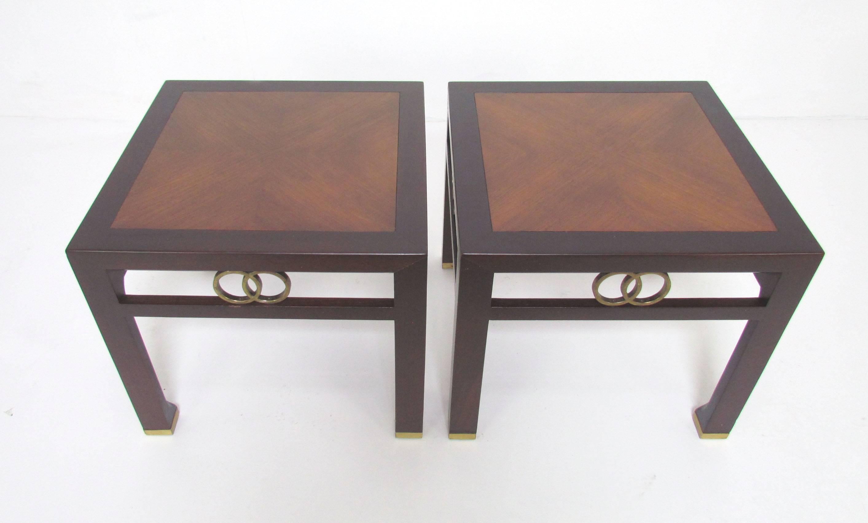Pair of end tables designed by Michael Taylor for Baker Furniture, circa 1960s. Decorative brass interlocking rings and leg sabots. Elegant cross grain top set off by a dark mahogany frame.