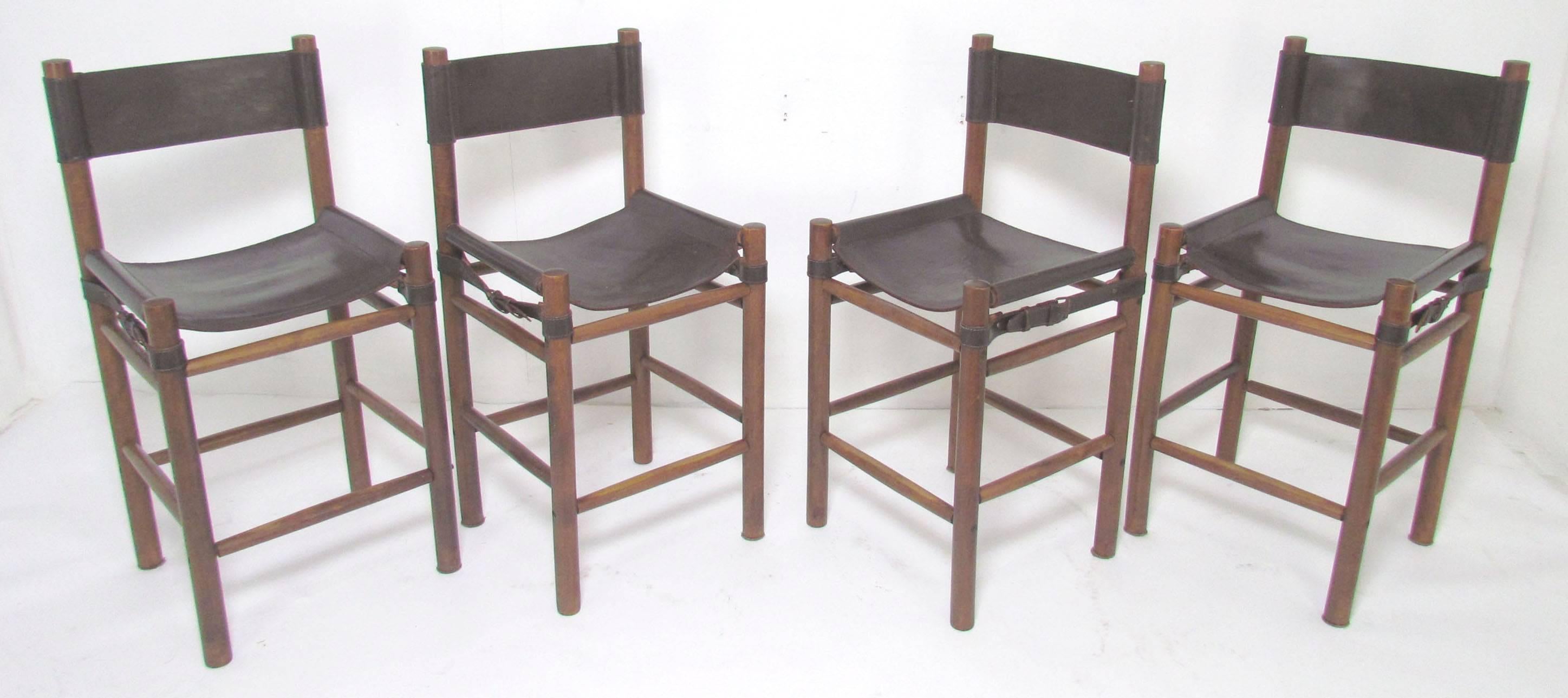 Set of four Safari style bar stools with leather sling upholstery and hardwood frames, made in Argentina, circa 1970s.