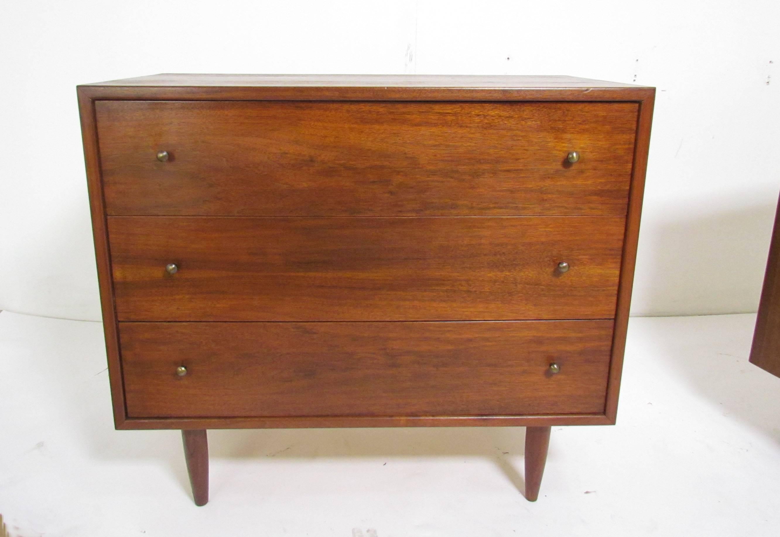Attractive pair of Mid-Century Modern three-drawer dressers in solid walnut with brass pulls, circa 1960s.