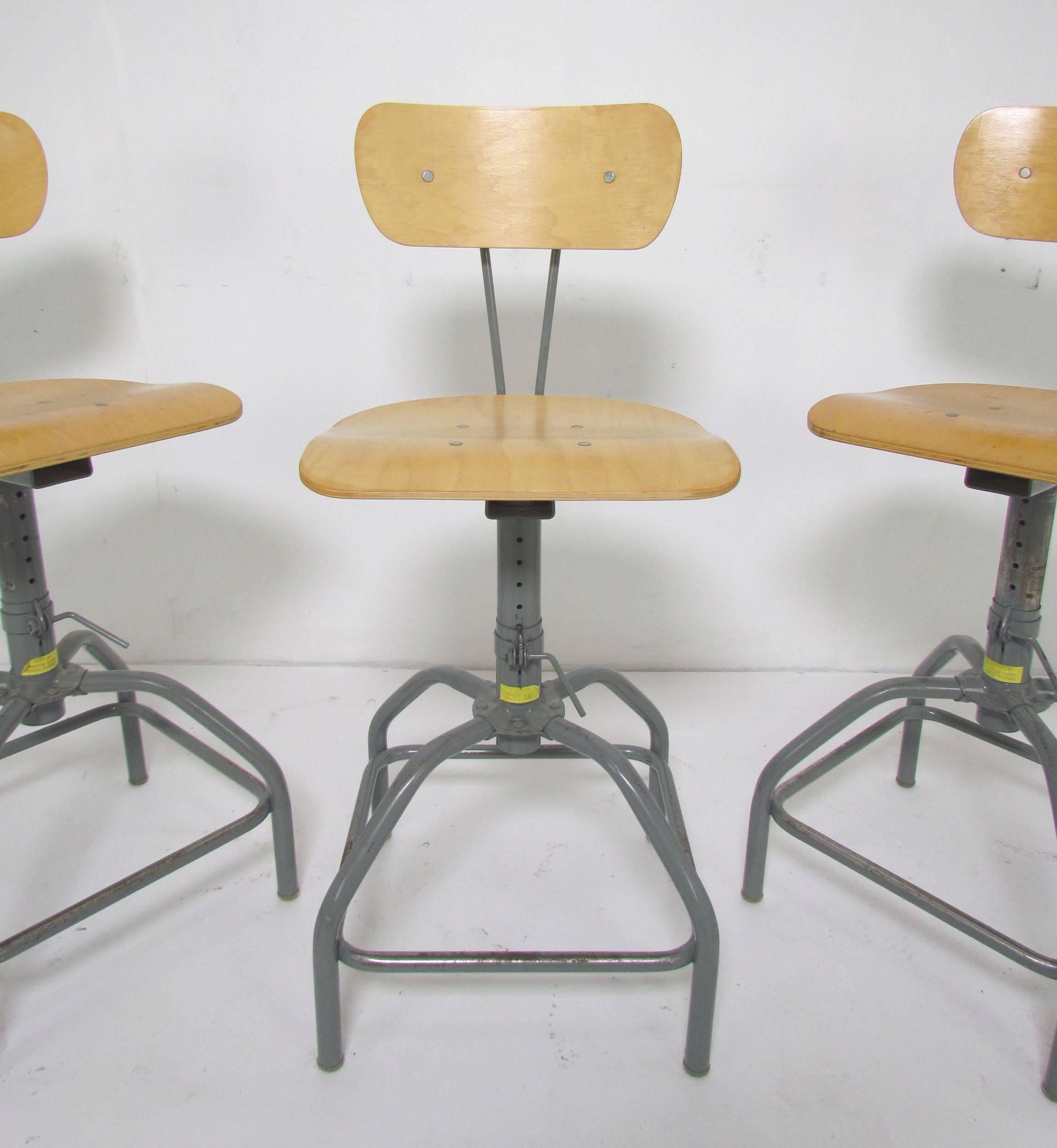 Set of three adjustable height laboratory stools, circa 1970s, with attractive split stem backs, these would make excellent Industrial design bar or counter stools.

Seat height is 25" at highest setting; adjust to a low of approximately