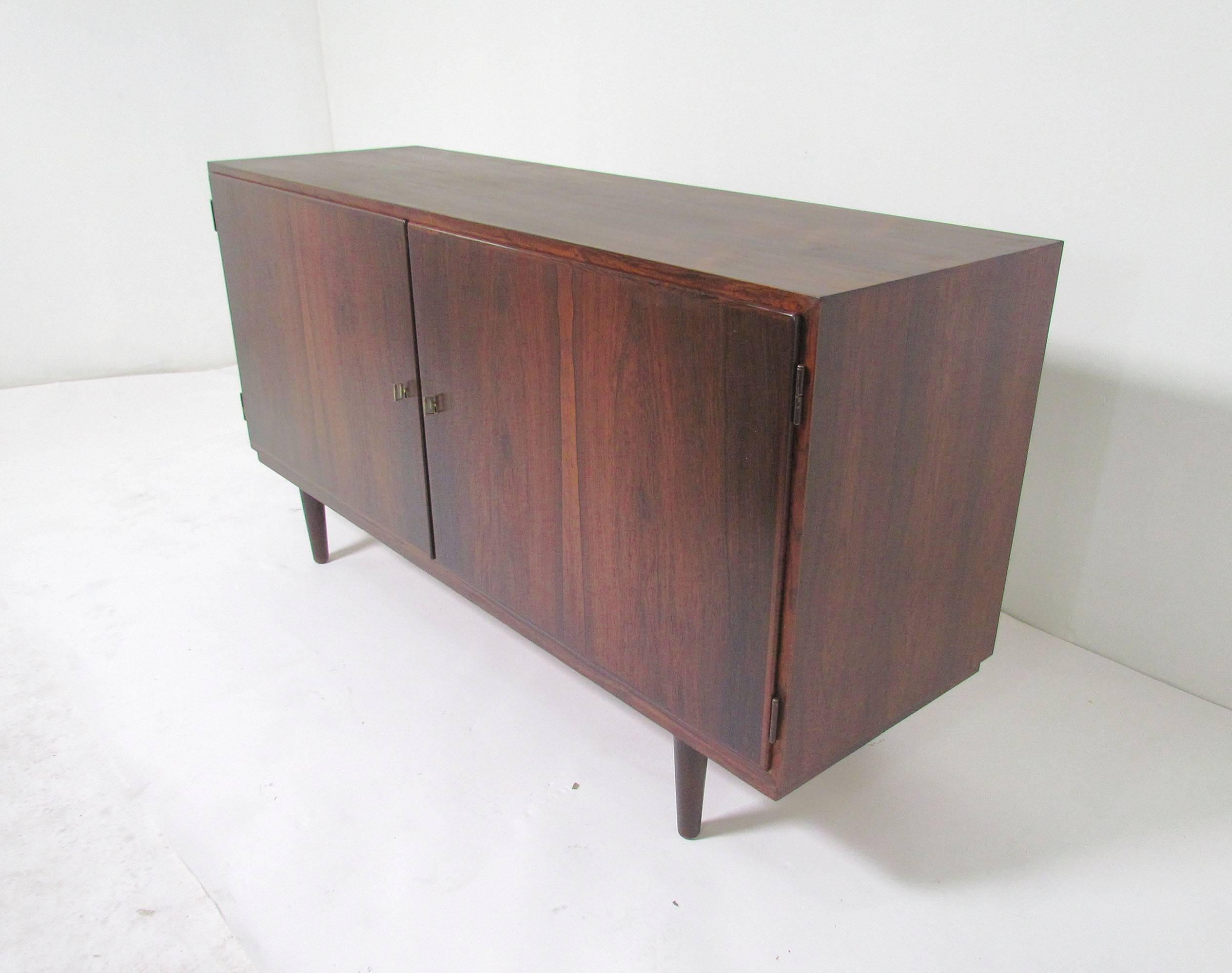Danish rosewood sideboard designed by Carlo Jensen for Poul Hundevad, circa late 1950s. Book matched locking doors, with a key for each, open to reveal flatware drawers and storage on one side, and adjustable shelves on the other. At 54.5