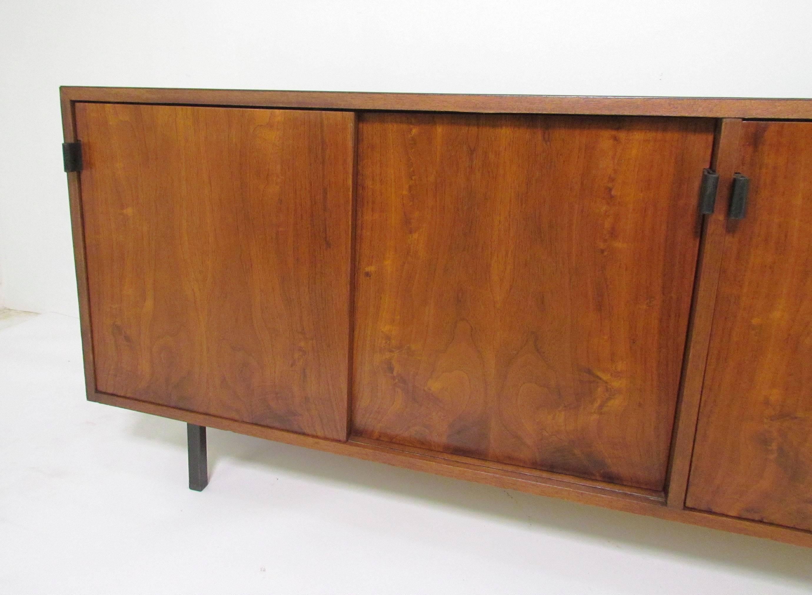 Florence Knoll credenza in walnut and mahogany with leather pulls, circa 1960s. Multiple adjustable shelves allow for internal configuration to suit ones needs.