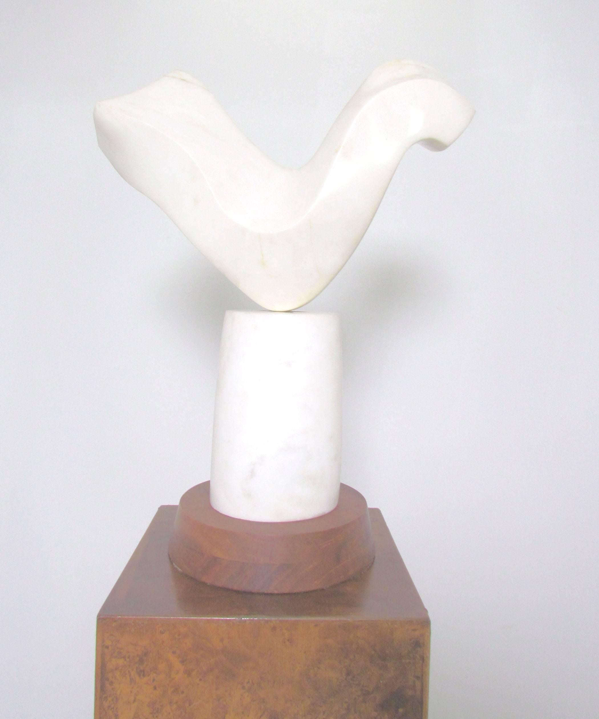 Abstract marble sculpture, signed M. Sokell and dated 1969. Paired with an Italian burl wood display pedestal.

Sculpture measures 8.75” diameter at base, 16.5” wide, 21” high. Burl pedestal measures 11” square by 39 ½” high. Together, this