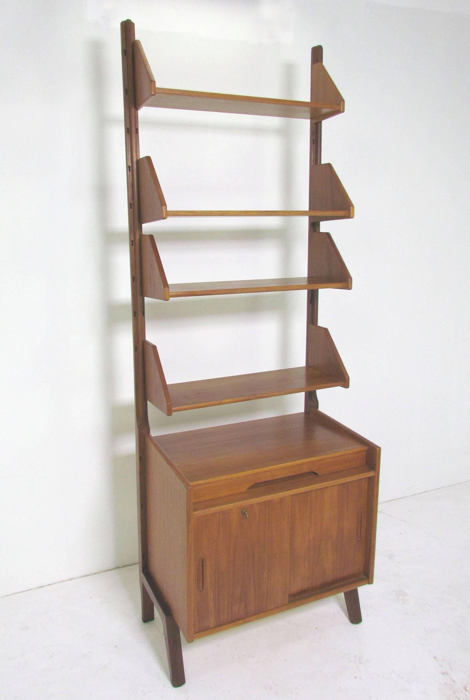 Danish teal free standing wall unit, consisting of a cabinet piece with locking mechanism and a shallow drawer, and four adjustable shelves with built-in book ends. In the manner of Poul Cadovius for Royal Systems.