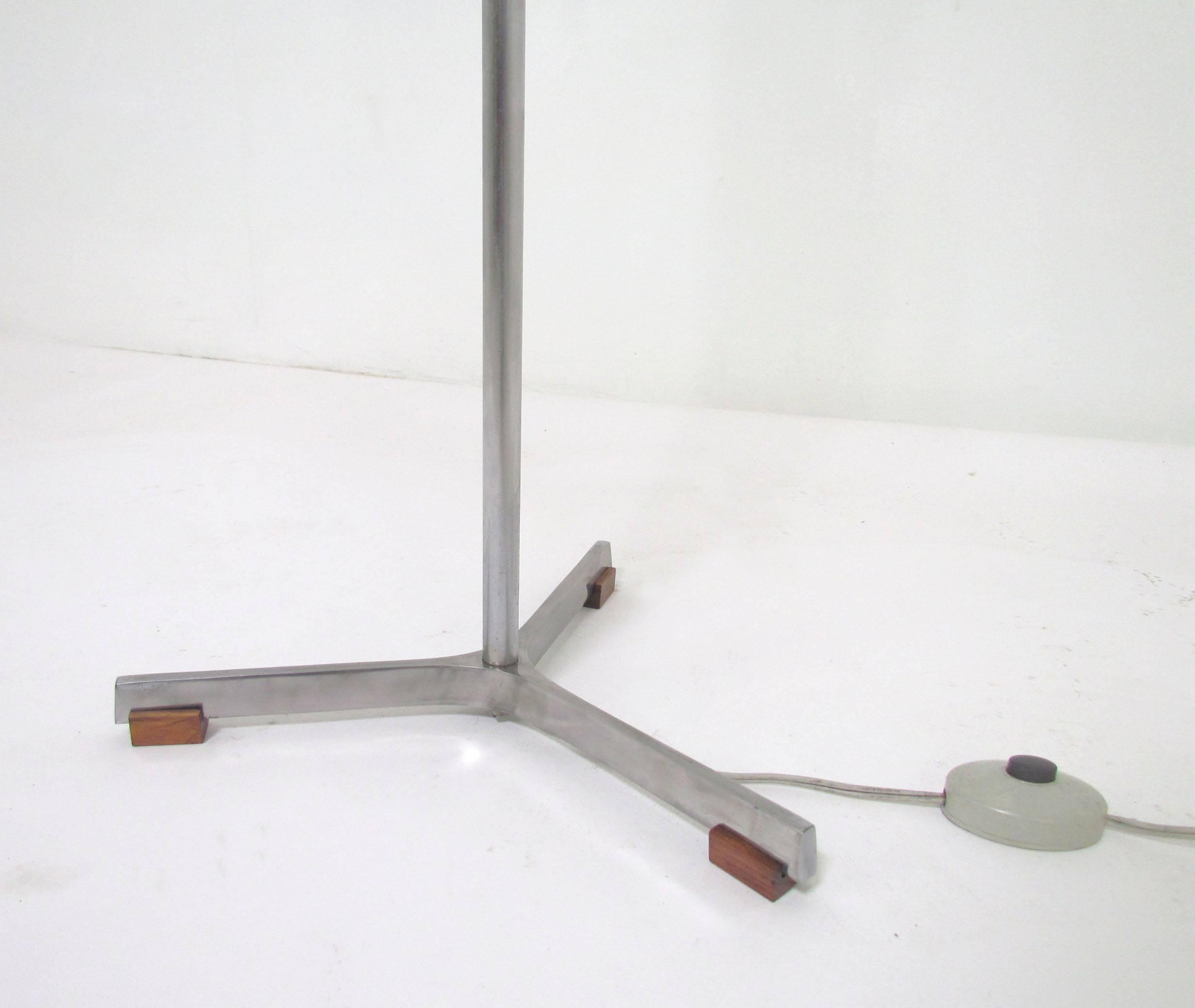 Danish floor lamp in aluminium with tripod base and rosewood "feet", designed by Jo Hammerborg for Fog & Morup, Denmark, circa 1960s. Unusually elongated finial and original linen lampshade.

Measures: 62" high to top of finial,