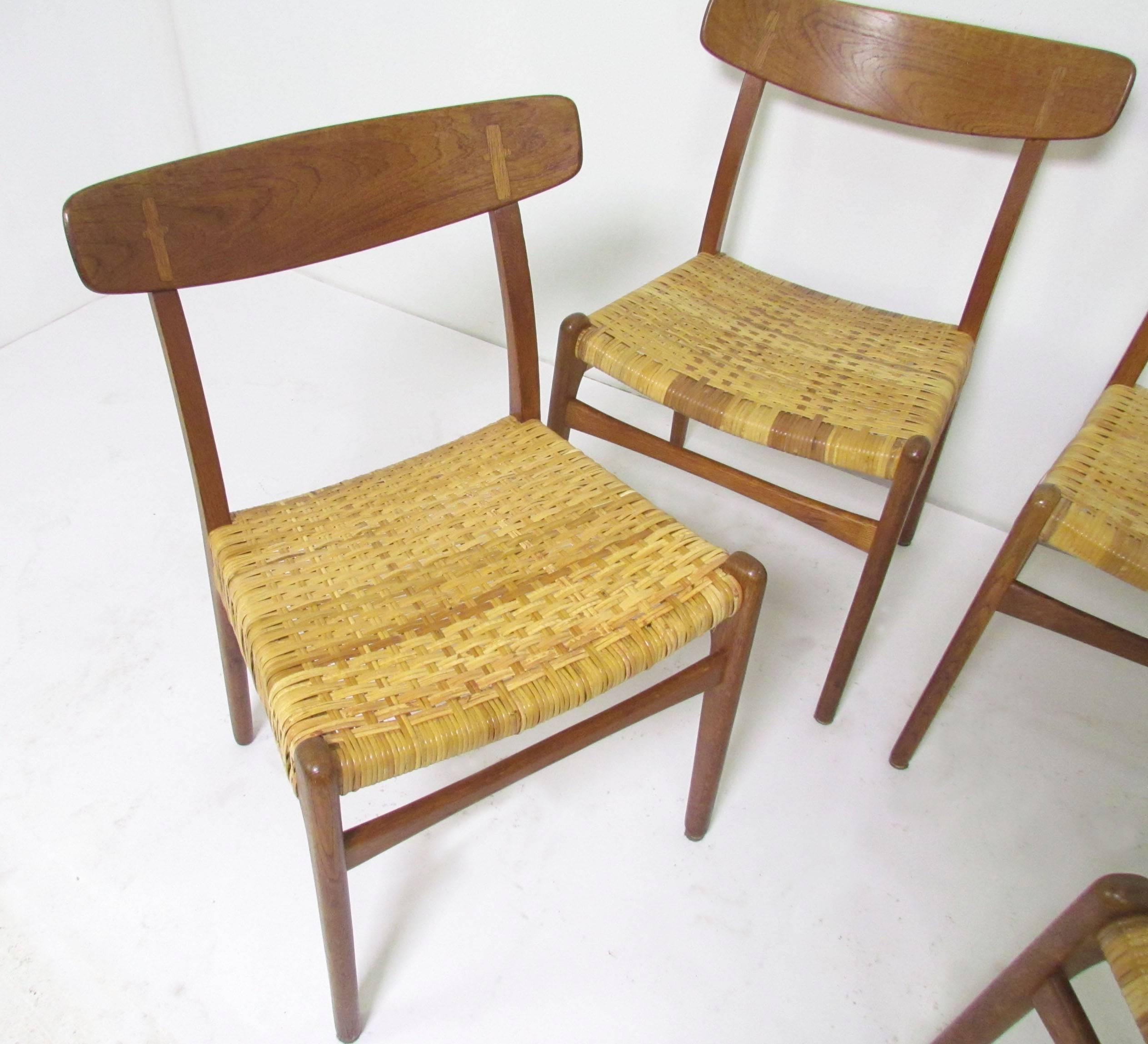 Set of four Hans Wegner CH-23 dining chairs in teak and oak with woven cane seats, circa 1950s.
