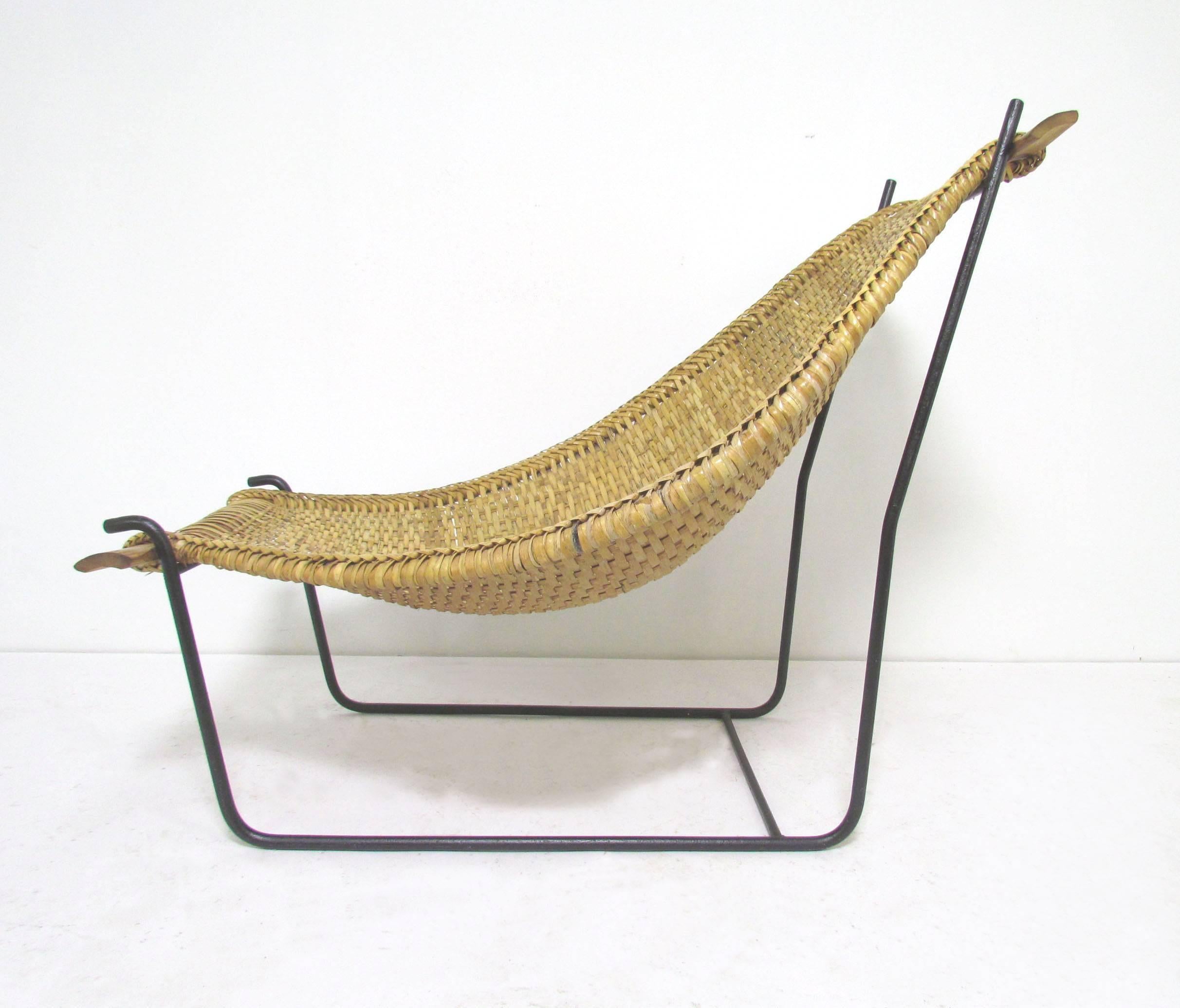 Hammock-form curvaceous sling chair in woven rattan on a wrought iron base, in the manner of John Risley's "Duyan" chair, circa 1950s.