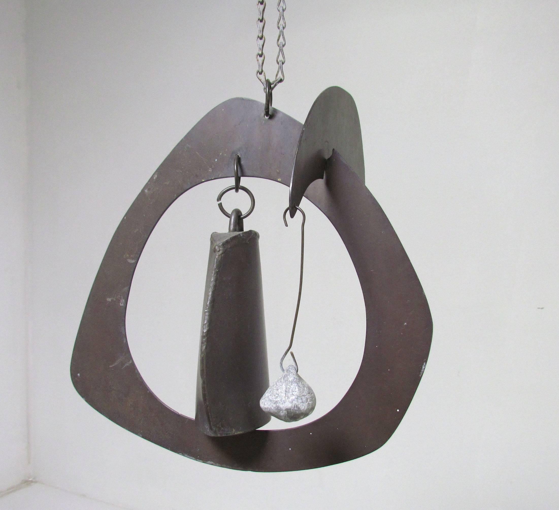 Handmade sculptural kinetic wind chime/ bell in folded and welded steel, counterbalanced with a crescent shaped arm and lead weight “clapper” to sound a low cow bell tone when the wind strikes just right. Signed with a mysteriously intriguing