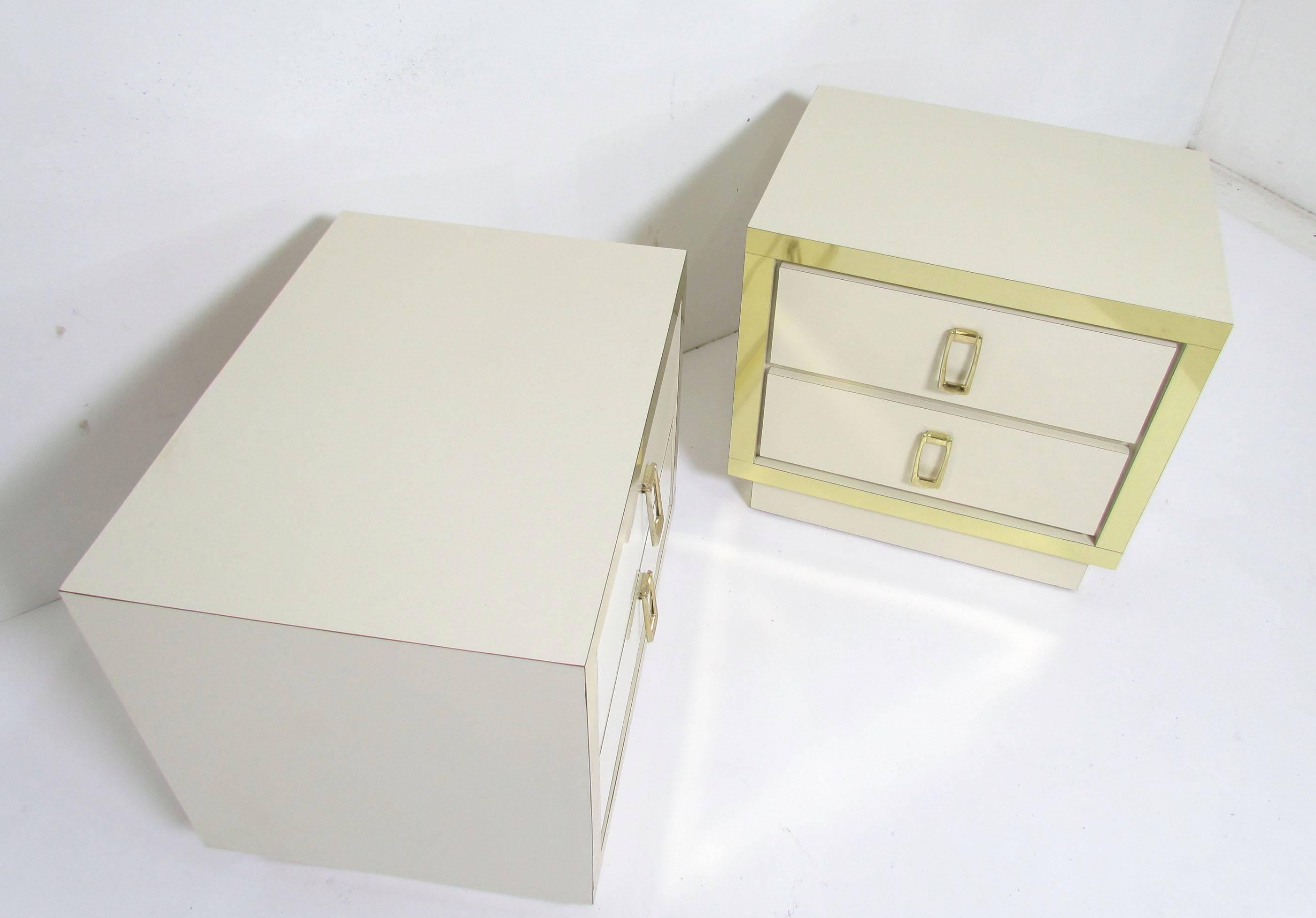 Fabulous pair of Hollywood Regency style nightstands or end tables, circa late 1970s-early 1980s, each with a two drawers. Well constructed of glossy laminate with brass hardware and border strip accents.