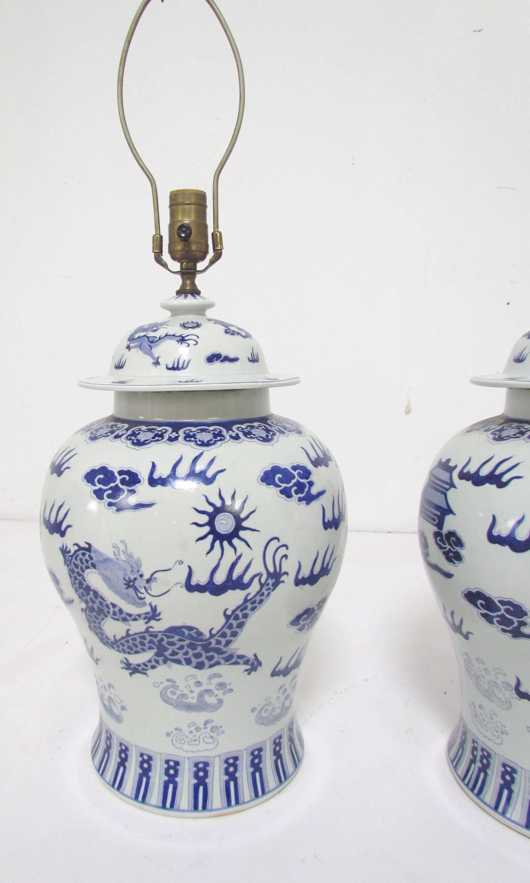 Pair of blue and white porcelain temple or ginger jar lamps with a Chinese dragon motif, circa late 19th century, converted to lamps, circa mid-20th century. 

Measure 29