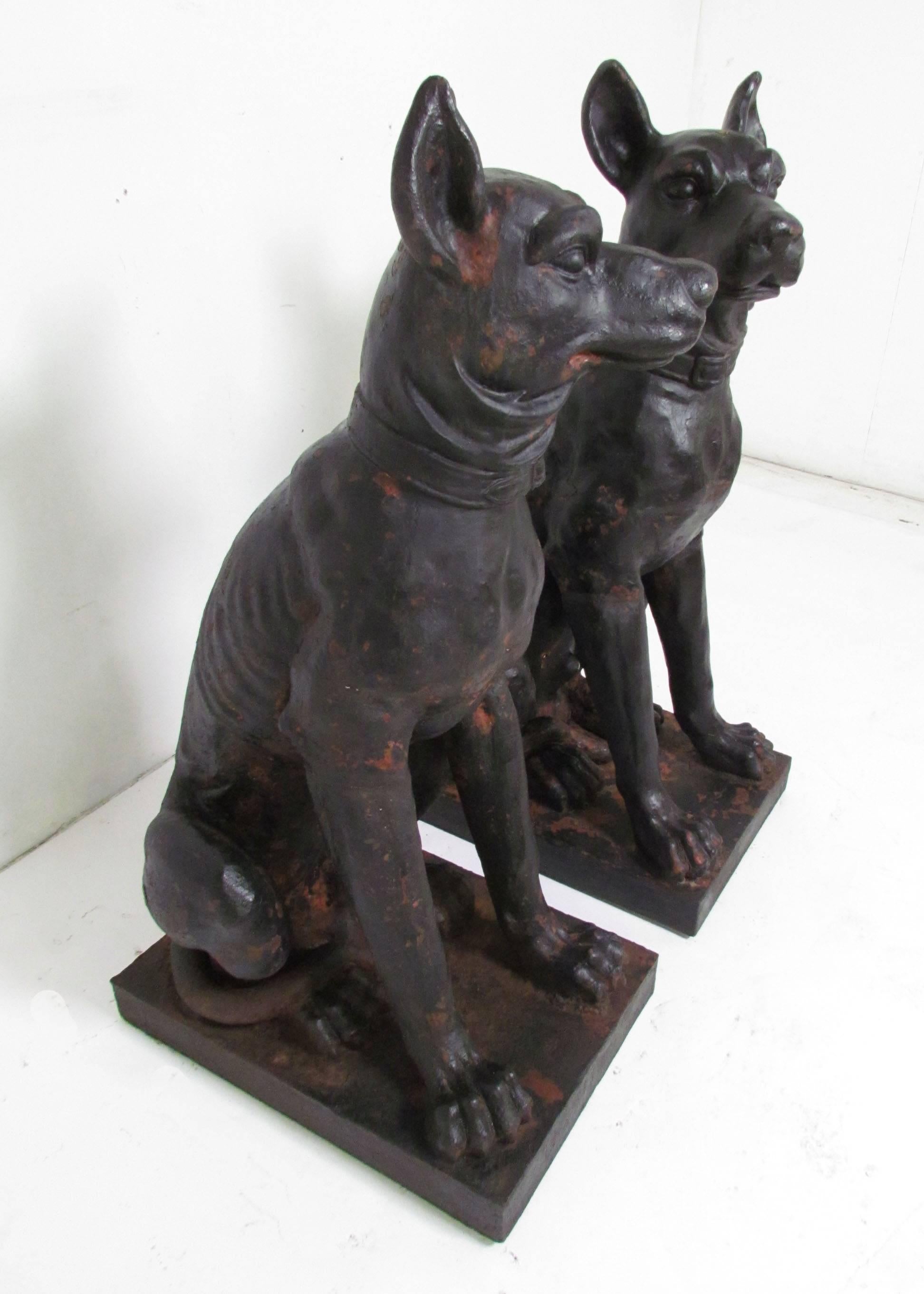 Pair of large-scale cast iron statues of guard dogs, French, circa early 19th century. A rare, true pair in original paint with traces of the underlying red clay bole visible.