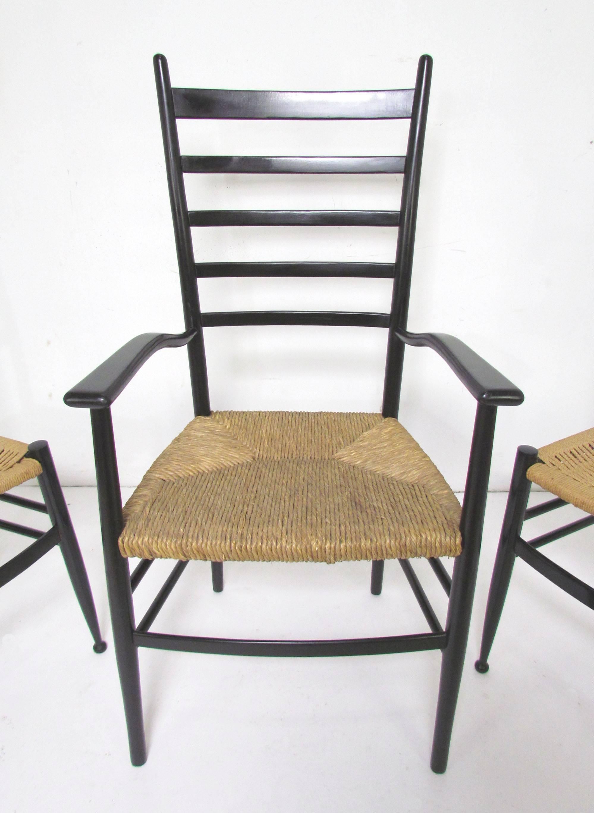 Set of Italian ladder back dining chairs in lacquered wood with woven seats, consisting of two arms and four sides, in the style of Gio Ponti. The side chairs are by Chiavari, imported by Otto Gerdau. The armchairs, with rush seats, are Italian of