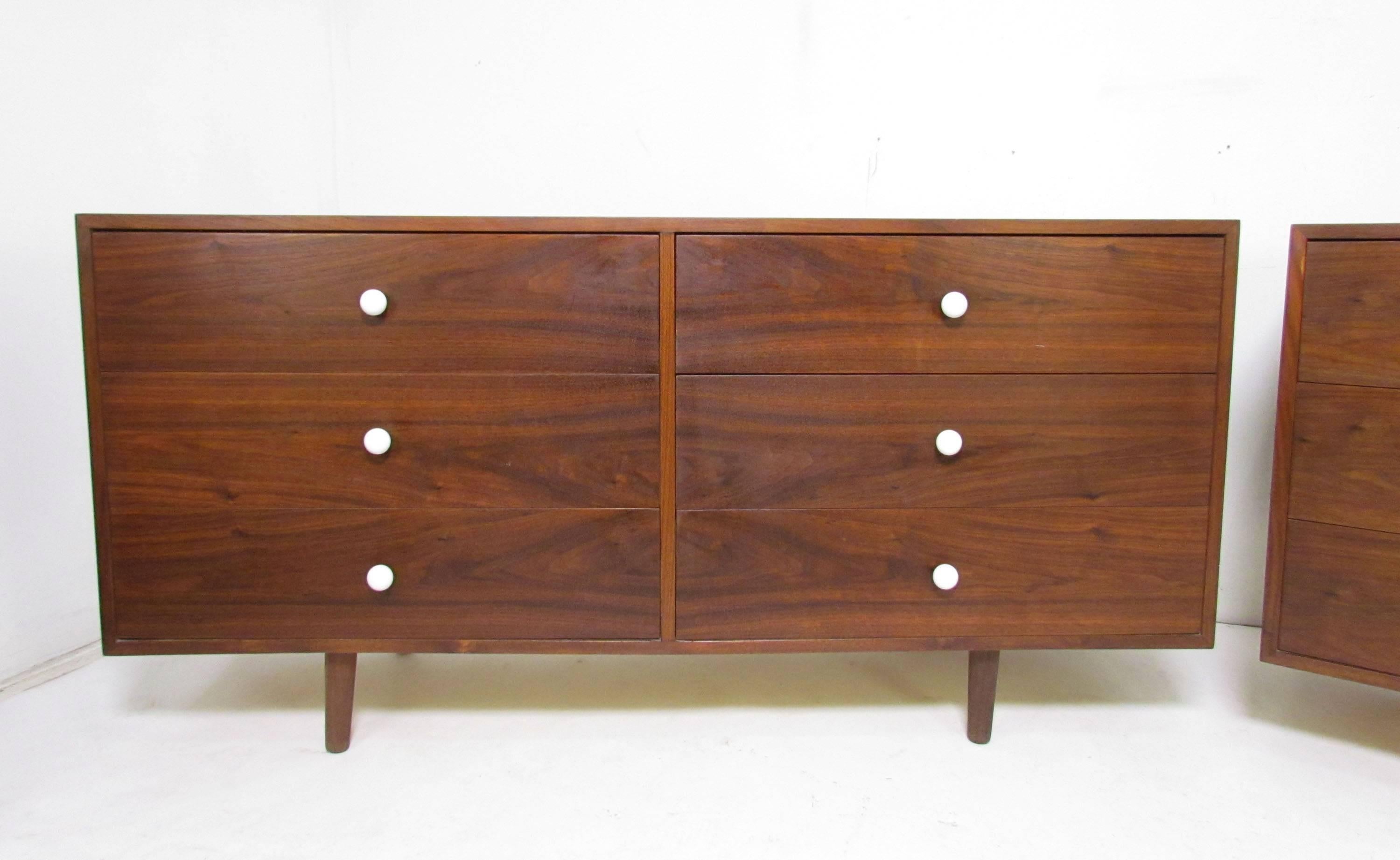 Pair of Mid-Century Modern long low chests of drawers in walnut with white ceramic ball pulls, in the manner of the Declaration Line designed by Kipp Stewart for Drexel. Unmarked, possibly custom-made, circa 1960s.