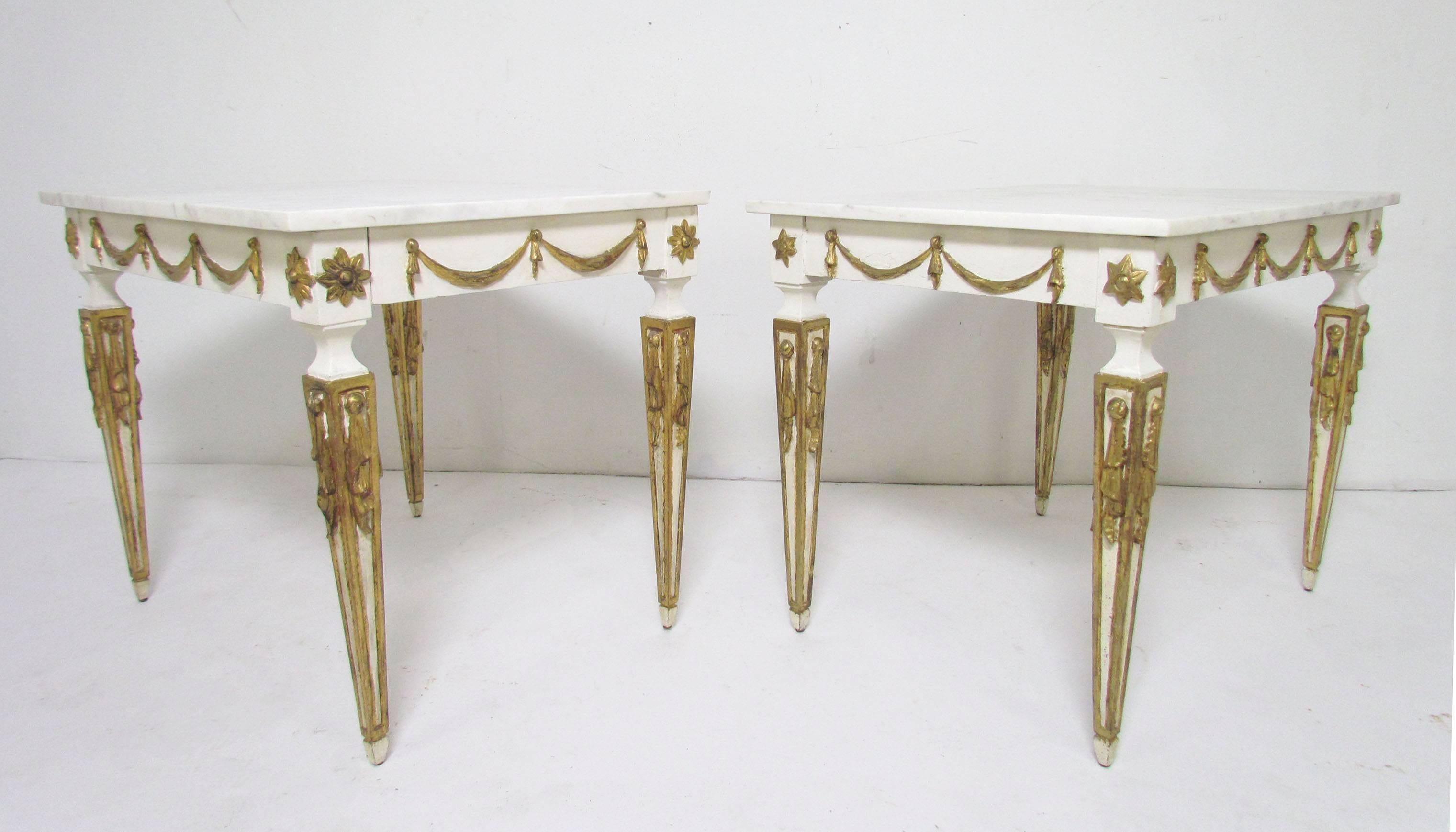 Pair of side tables, made in Italy, painted wood with parcel-gilt decoration, marble tops, circa 1960s. 

Due to their hand built nature, there are slight variations to the carvings. One is also 1/2