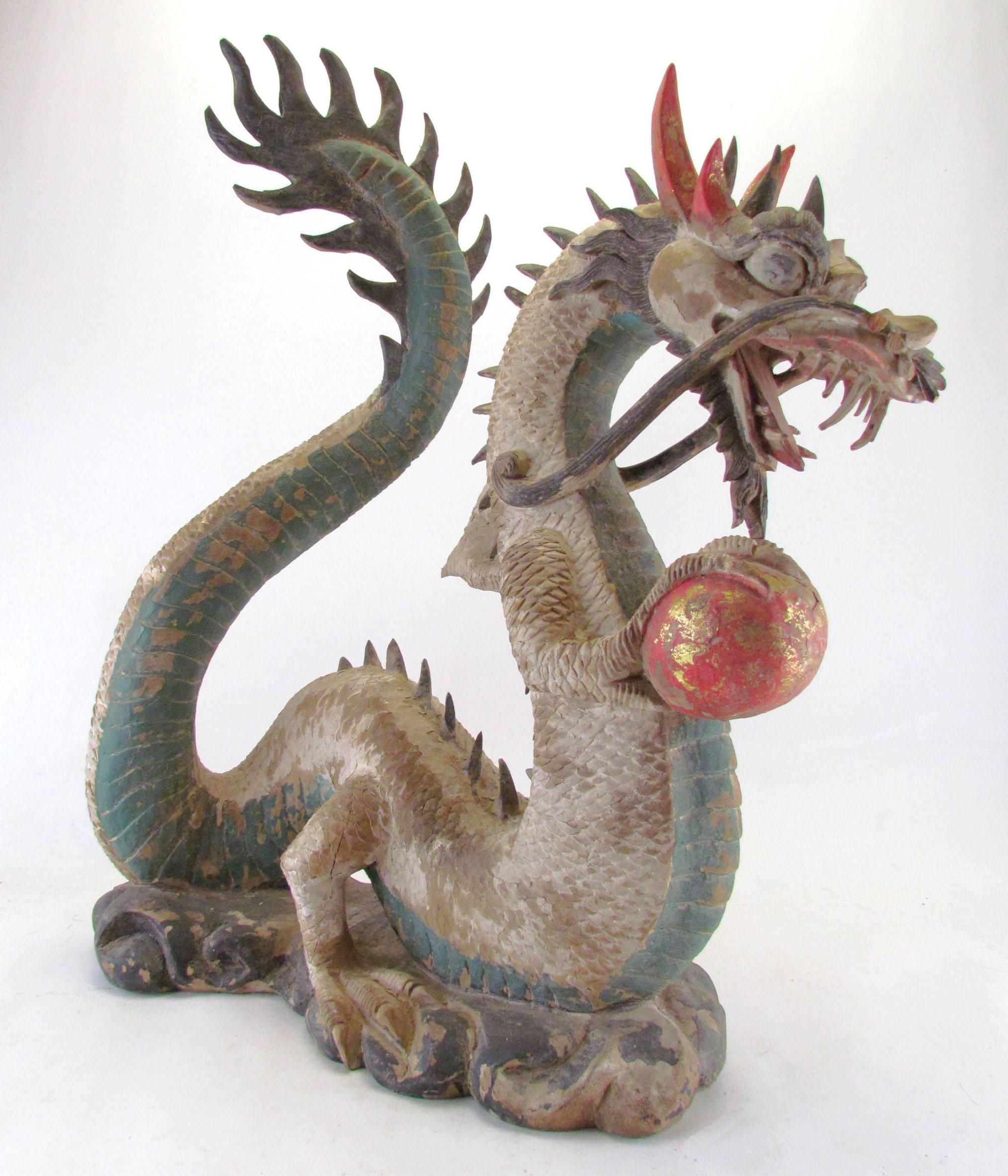 An exquisitely carved Chinese dragon, circa 19th century in original paint. The colorful horned creature clutches a flaming pearl, a feature from ancient Chinese legend.