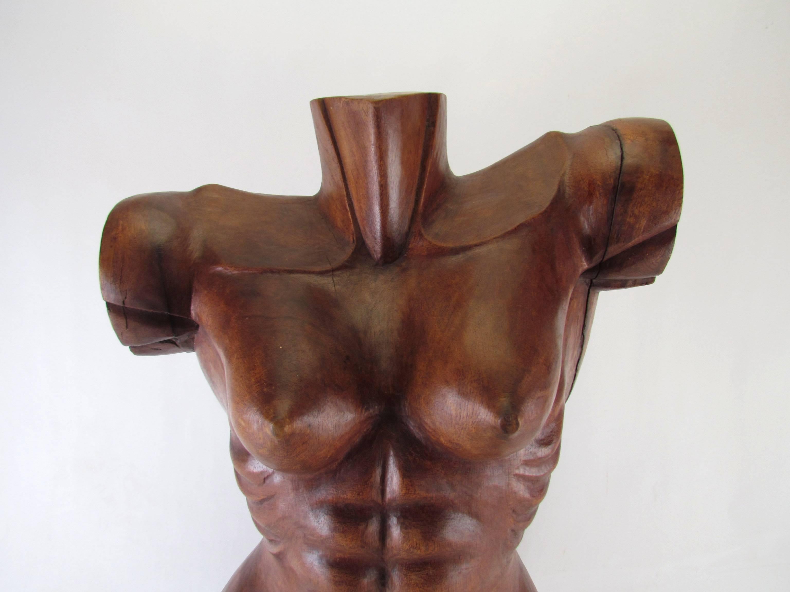 A striking hand-carved wooden torso sculpture of an unusually toned female, signed 