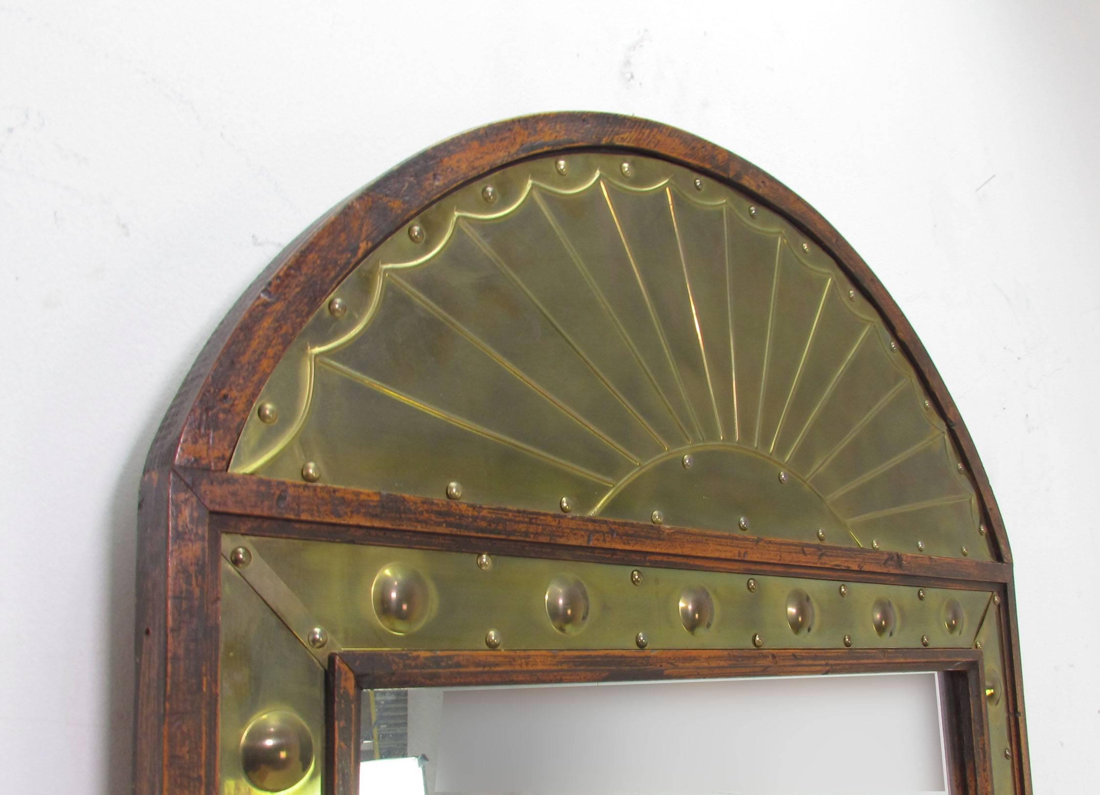 Hollywood Regency style wall mirror by Sarreid with brass repoussé panels set into a wooden frame. Made in Italy, circa 1970s.