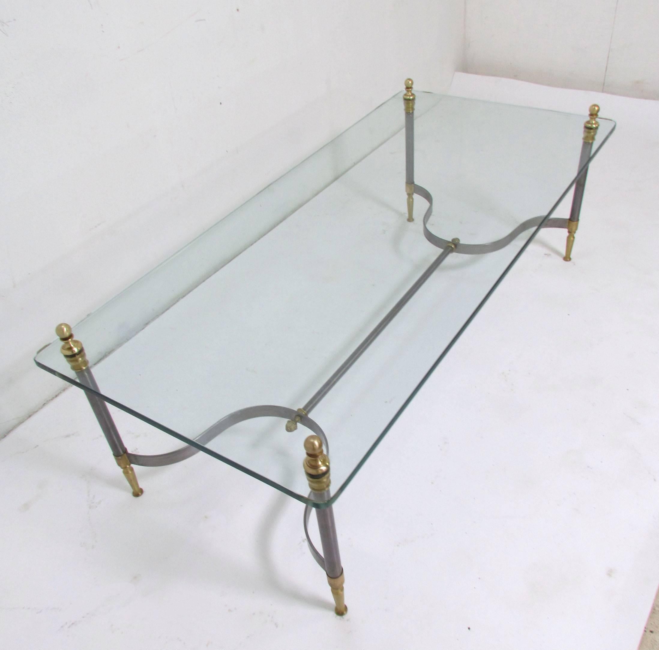 Stylish coffee table in brushed steel and brass in the manner of Maison Jansen, with polished edge glass top and through-post construction, circa 1960s.

Measures: 16