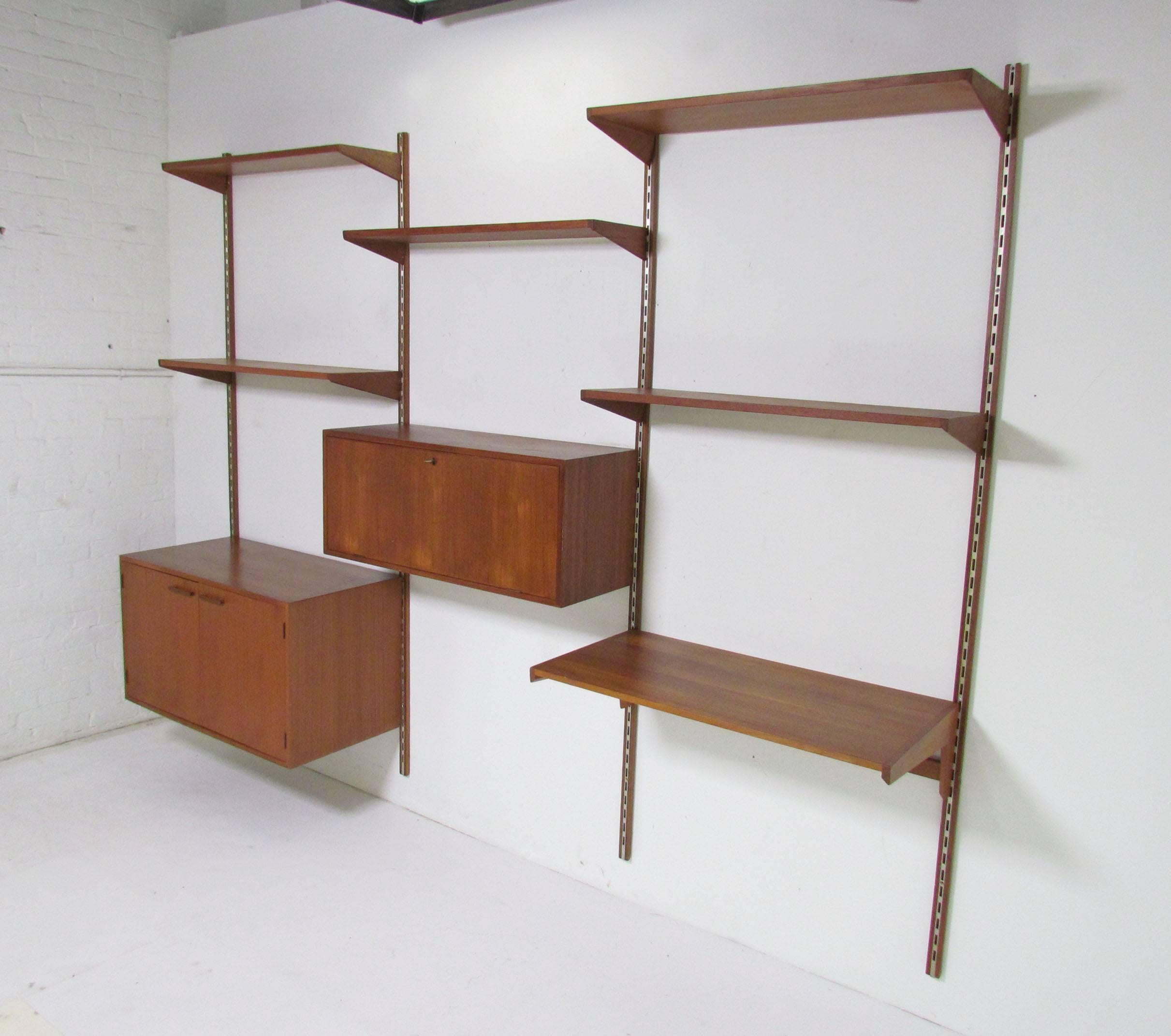 Danish teak wall-mounted shelving unit designed by Kai Kristiansen for Fornem Møbelkunst, circa early 1960s. Three bay unit consists of a desk top, a two-door cabinet with ample interior storage, and a drop-front cabinet with additional storage, as