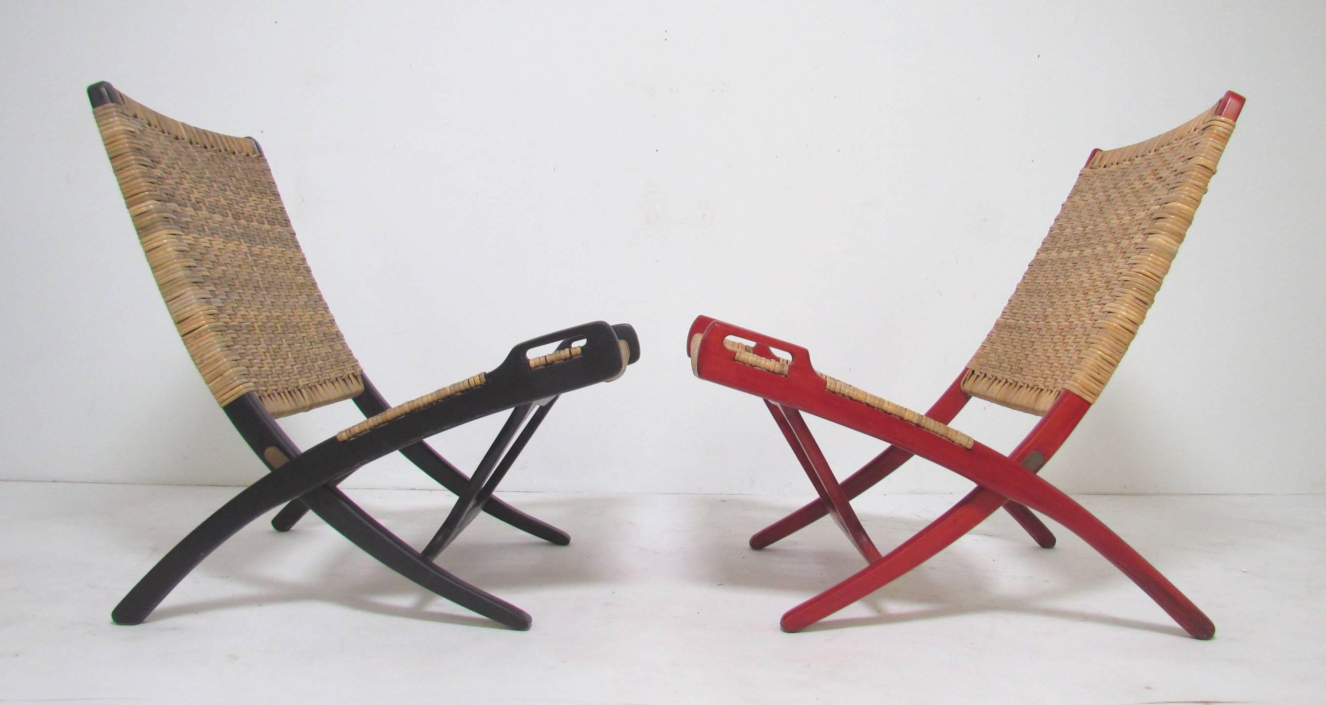 Pair of Mid-Century folding safari chairs in cane with original stained wood frames, in the manner of the iconic folding chair in cane designed by Hans Wegner for Johannes Andersen. 

Unmarked, but attributed to Ebert Wels. Slight nearly