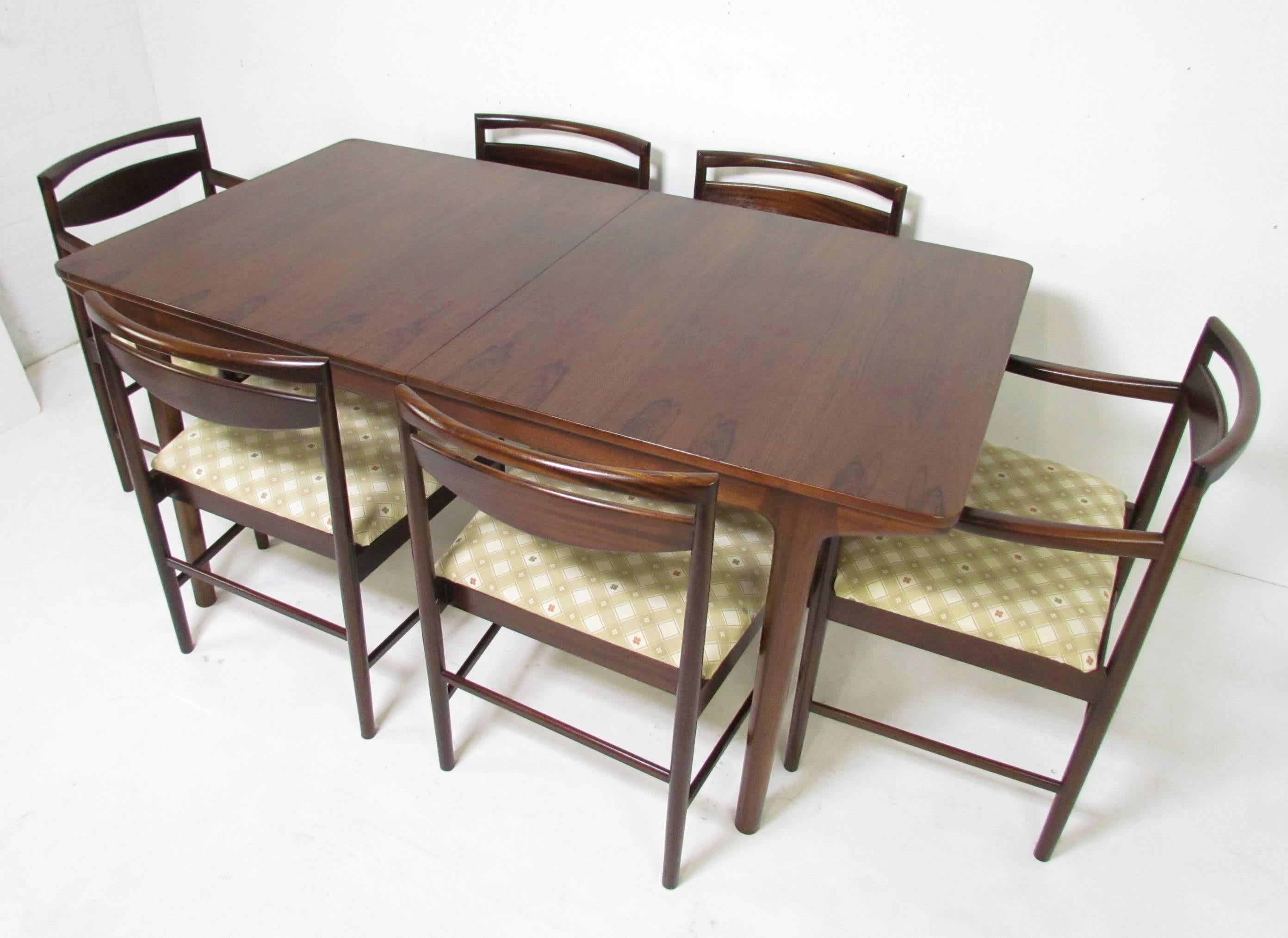 Mid-Century dining set in rosewood, designed by T.R.L. Robertson for A.H. McIntosh, Scotland. Set includes six chairs (four sides, two arm chairs). Table includes two hidden butterfly extension leaves. Table signed with McIntosh label and date