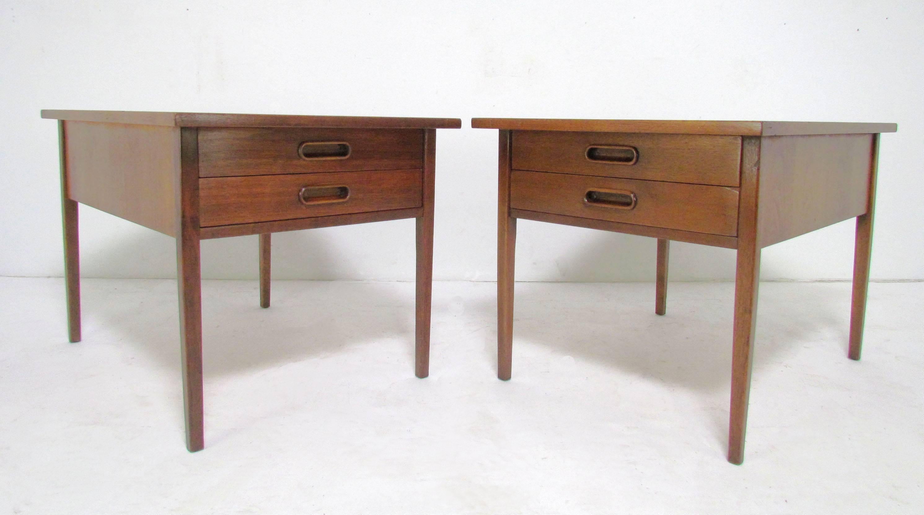 Pair of walnut and teak end tables, each with two drawers with carved pulls in the manner of Arne Vodder.