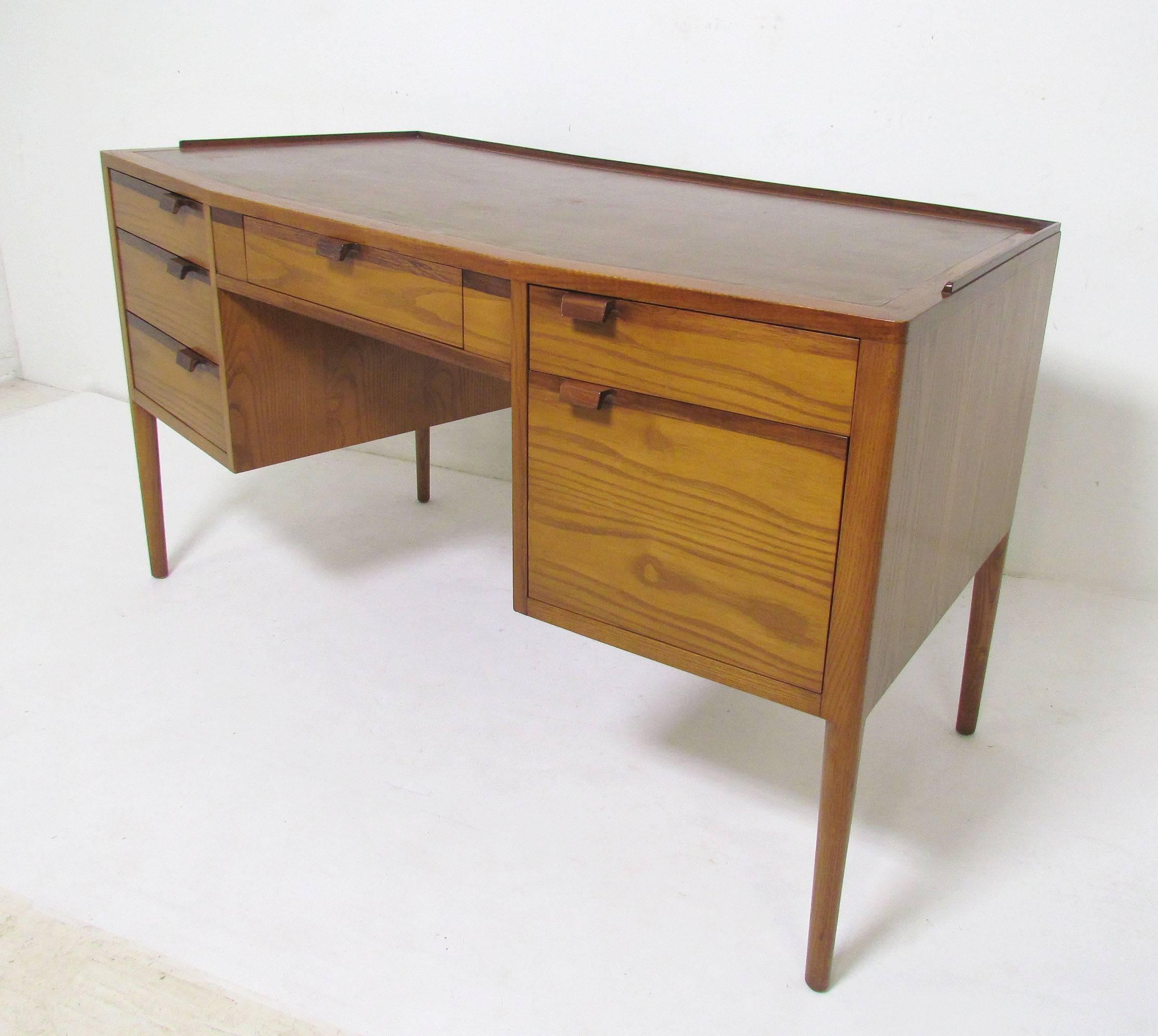 Elegant Edward Wormley for Dunbar writing desk in walnut with contrasting rosewood drawer handles and accents. Stylishly fanned top with pencil rail and a leather top. File drawer can be configured for letter or legal size.