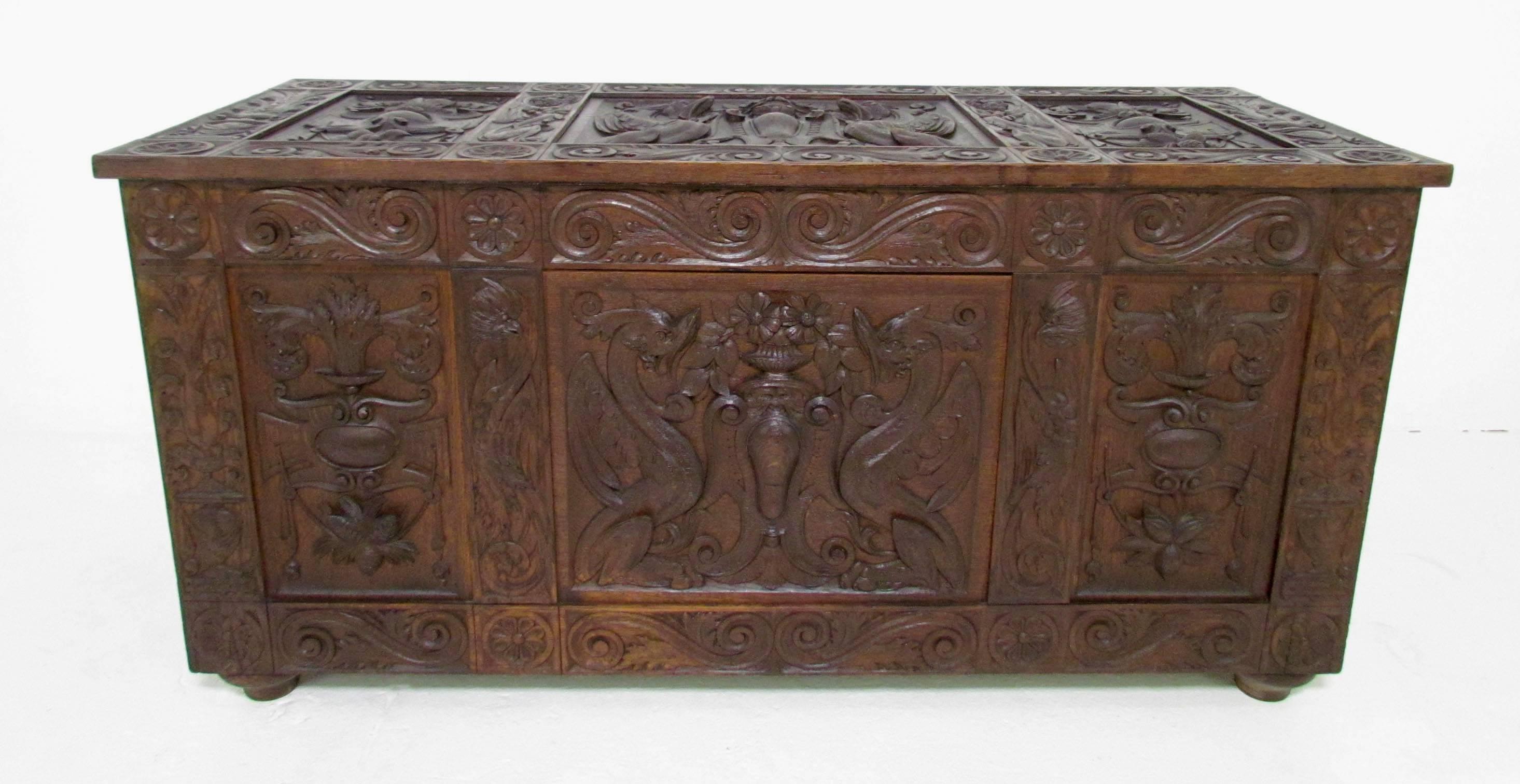 Exceptional 19th century baroque revival Italian cassone or wedding chest. Meticulously hand carved top and side panels decorated with mythological depictions of a central pair of Griffins flanking an urn of flowers as well as the heads of birds and