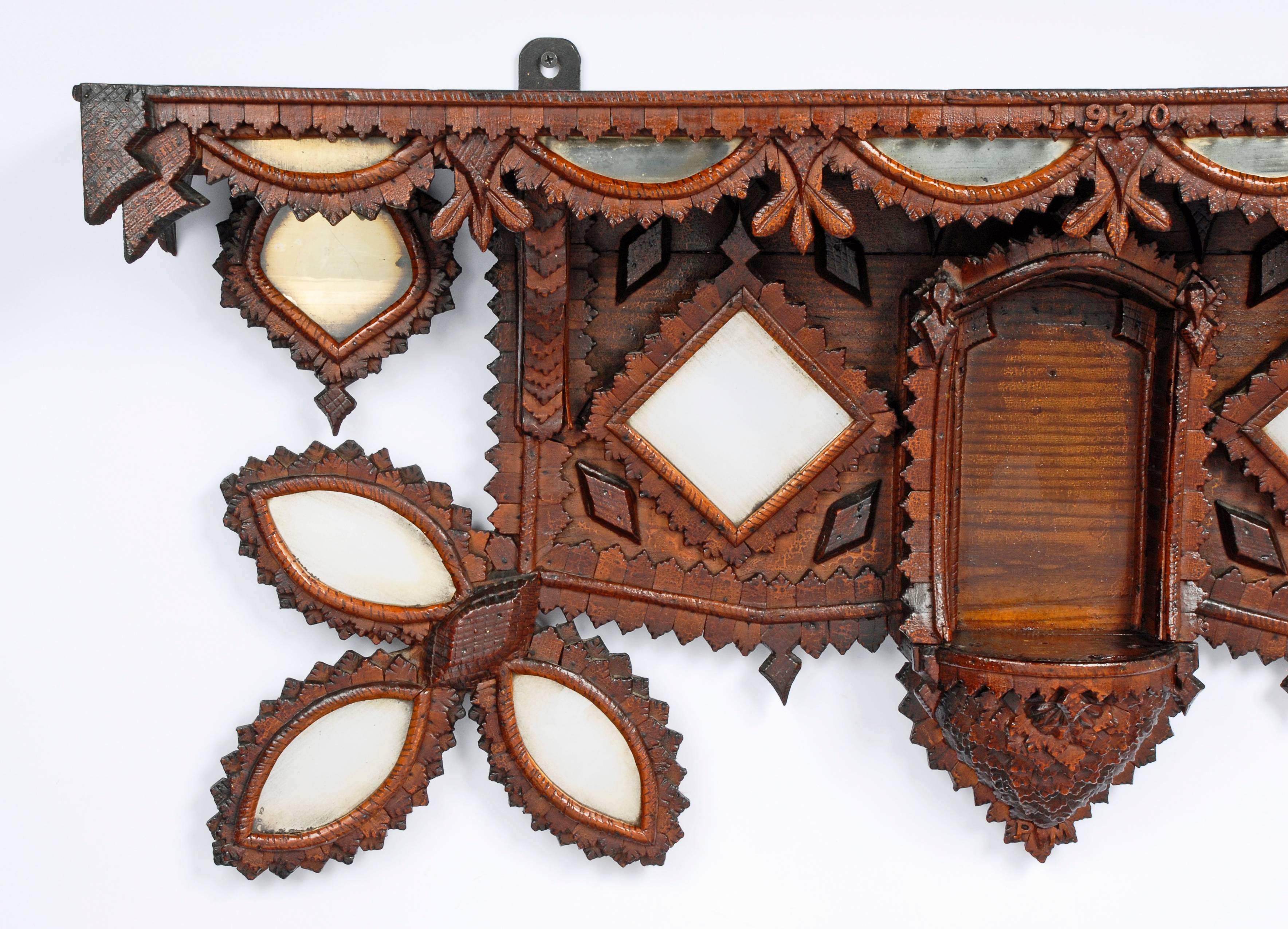 A breathtaking Tramp Art shelf with inset mirrors and dated 1920. The bottom mirrors are extended in floral patterns and the profusion of mirrors give the shelf a brilliant appearance. Heavily detailed with hundreds of applied pieces. The bottom