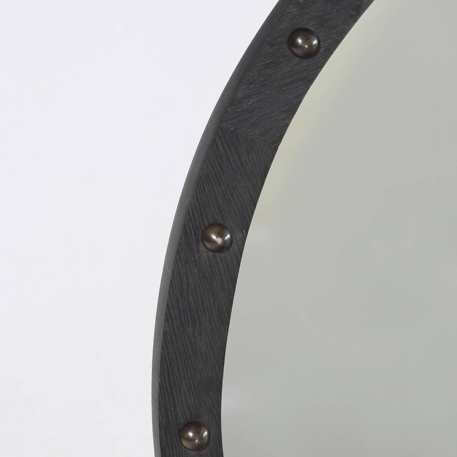 A lovely round mirror in Brazilian Exotic Hardwood with a sculpted edge and adorned with patinated bronze half circles. This mirror has a charcoal oil finished with dark patina brass details. 

Many pieces are stored in our warehouse, so please