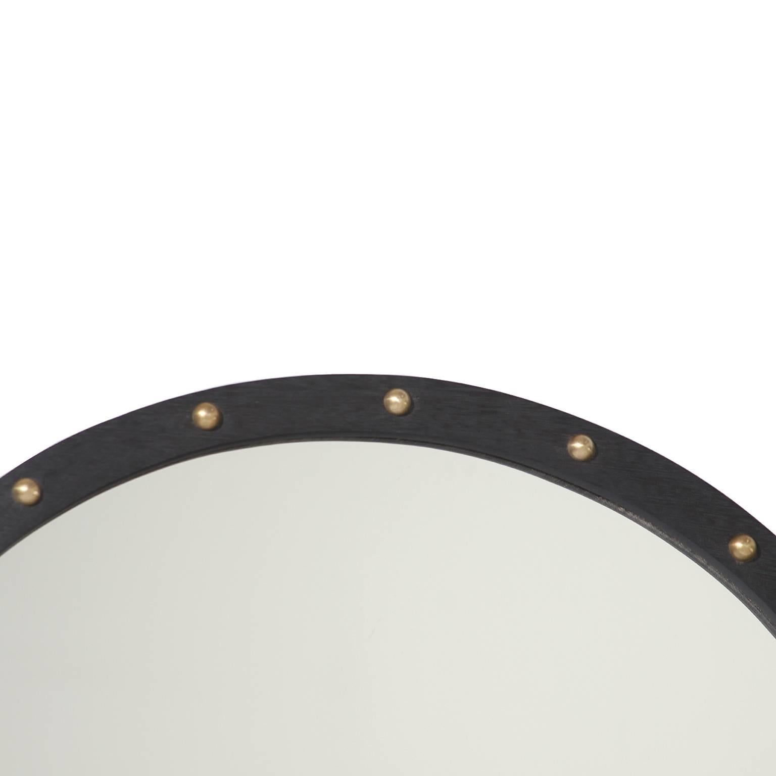A lovely round mirror in Brazilian Exotic Hardwood with a sculpted edge and adorned with patinated bronze half circles. This mirror has a charcoal oil finished with brushed brass details. 

We have four available 

Many pieces are stored in our