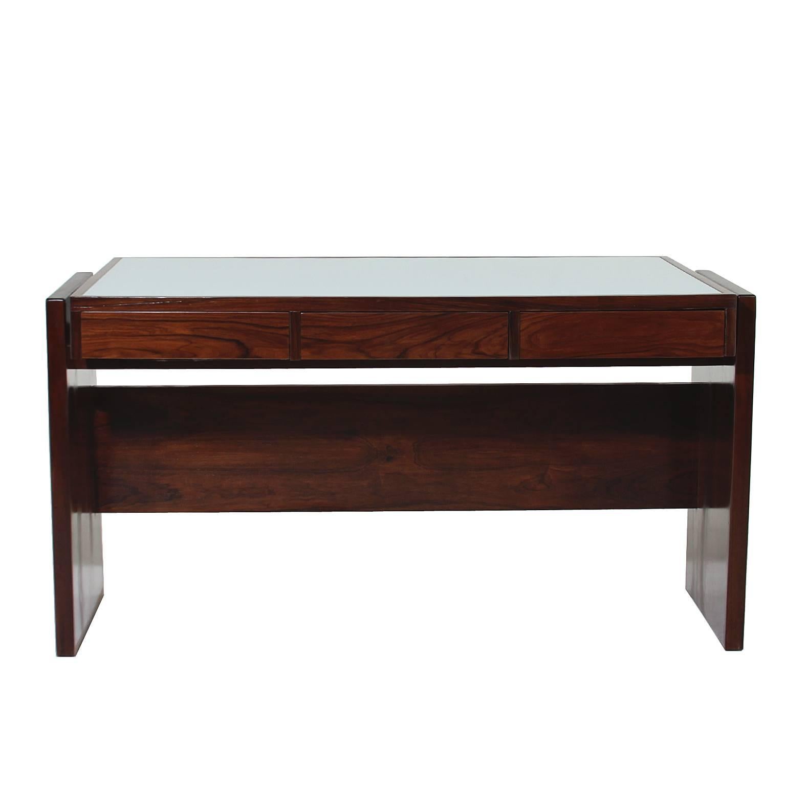 Hardwood desk designed by Brazil's Joaquim Tenreiro with a white reverse painted glass top and three drawers. This desk came from the Bloch, Editores headquarters, a building designed by Oscar Niemeyer and with interiors furnished by Sergio